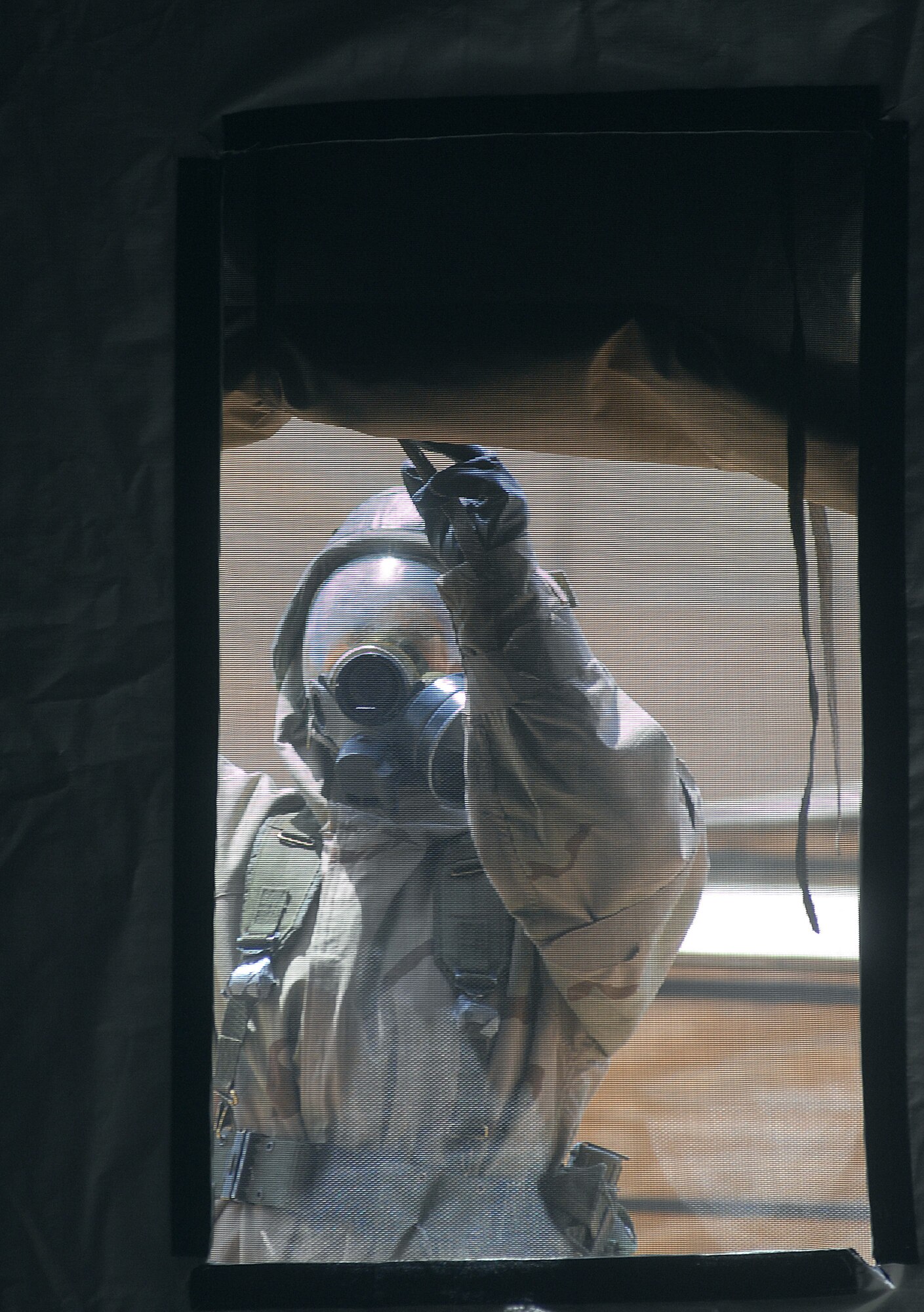 Cadet Selena Roots rolls up a tent flap after a "chemical attack" July 13 during Global Engagement, a summer course at the U.S. Air Force Academy in Colorado Springs, Colo.  Global Engagement teaches cadets the expeditionary Air Force concept of deploying, establishing a bare-base operation, executing their mission, defending their base and re-deploying home.  (U.S. Air Force photo/Tech. Sgt. Larry A. Simmons) 