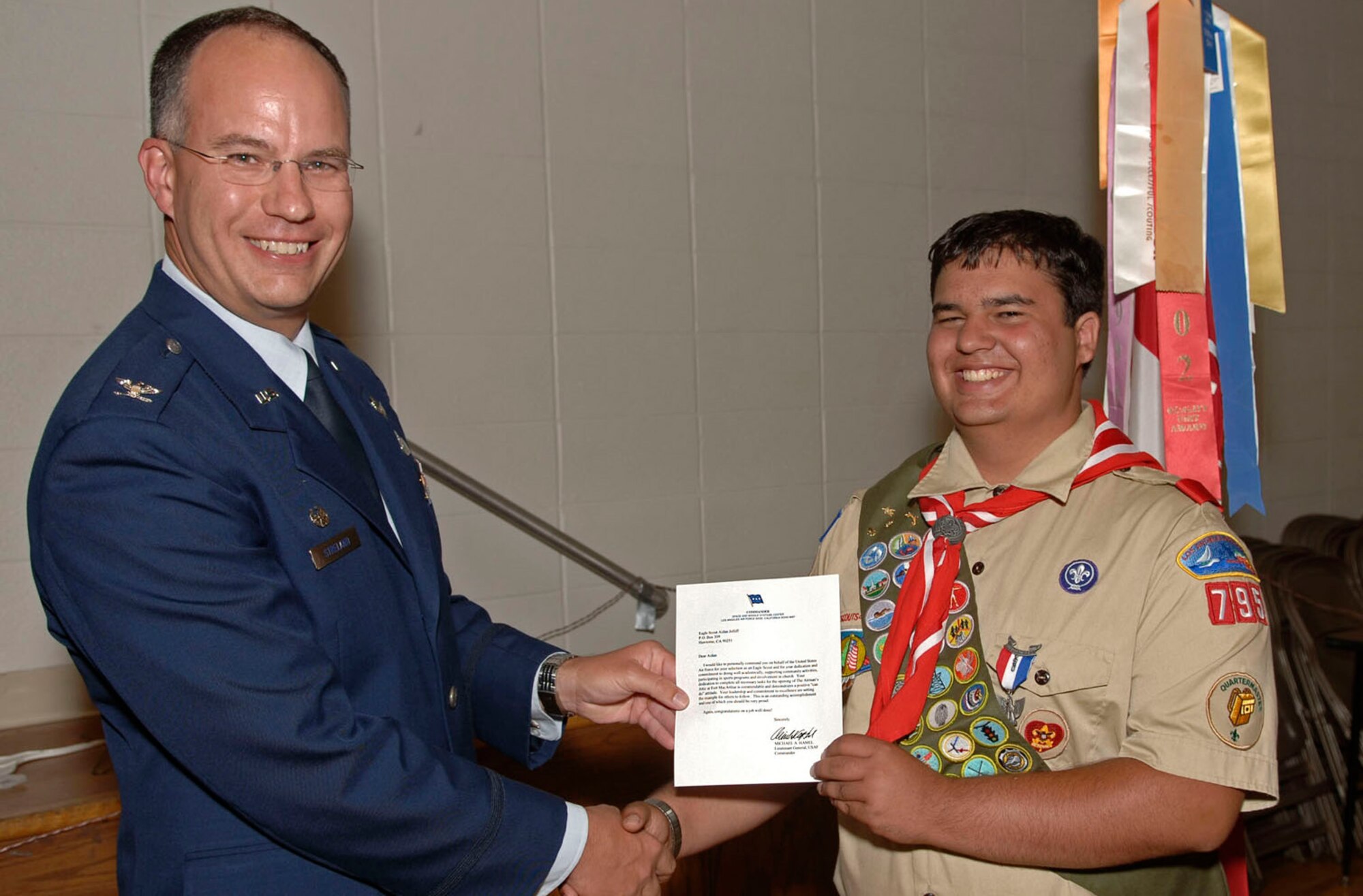 Colonel Arnold Streland, MILSATCOM Systems Wing, presented a letter of appreciation from Lt. Gen Hamel and a SMC coin to H. Aidan Jolliff, an Eagle Scout and member of Lawndale Scout Troop 795, at an Eagle Scout Court of Honor ceremony, July 21. Aidan’s Eagle Scout project involved taking the Airman's Attic at Fort MacArthur from an empty room to a functioning facility. (Photo by Paul Testerman)