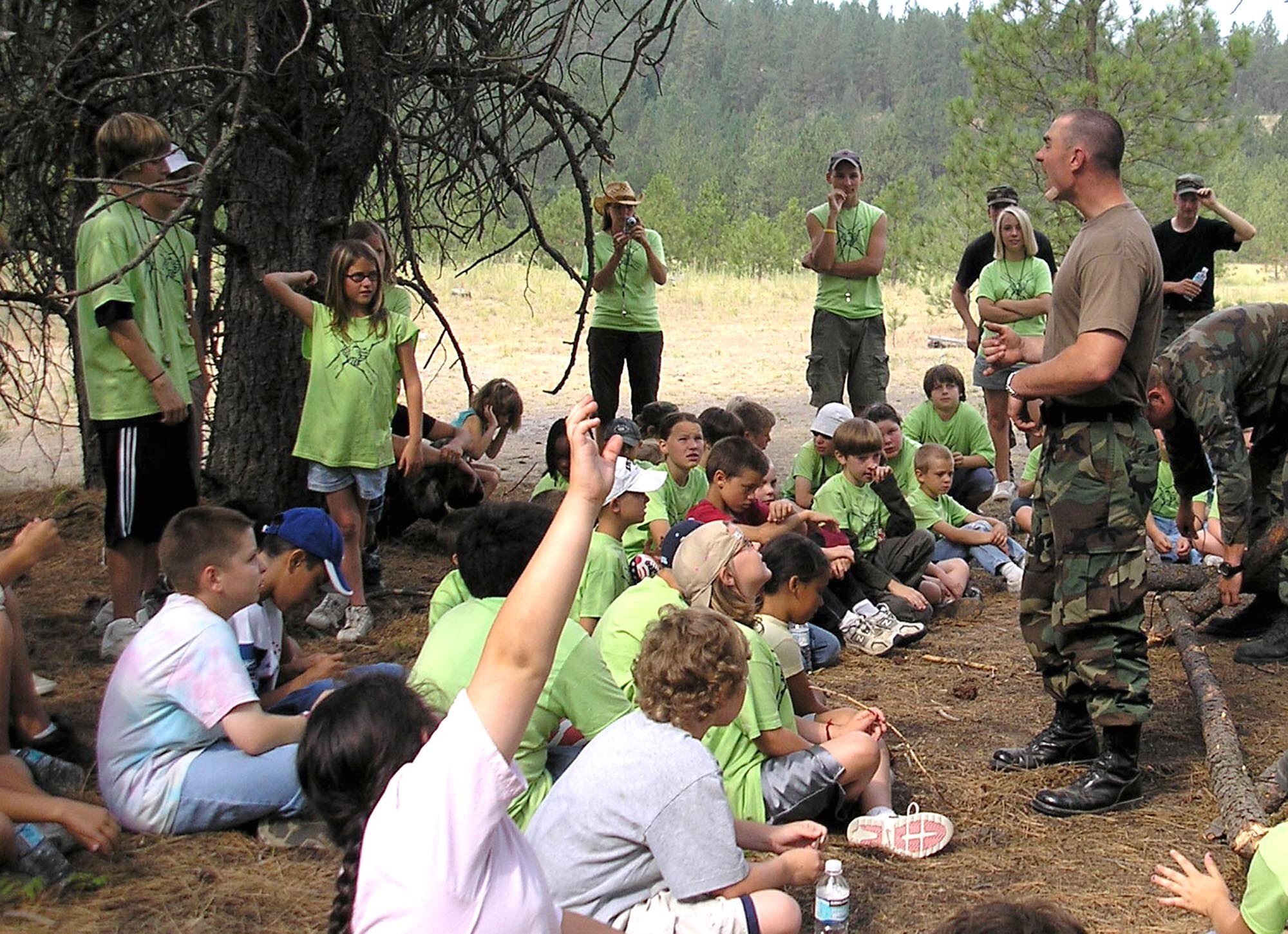 SPOKANE, Wash. – Survival, Evasion, Resistance and Escape instructor Airman 1st Class Daniel Foret speaks with children attending the Blue Green Summer Youth Camp here, held July 16 - 20.  The children learned to make a shelter in the wilderness, read a compass, pack an animal and repel from rocks during the camp. The camp gives priority to children with a deployed parent, and is open to families of all services and components. (U.S. Air Force photo/ Melissa Still)