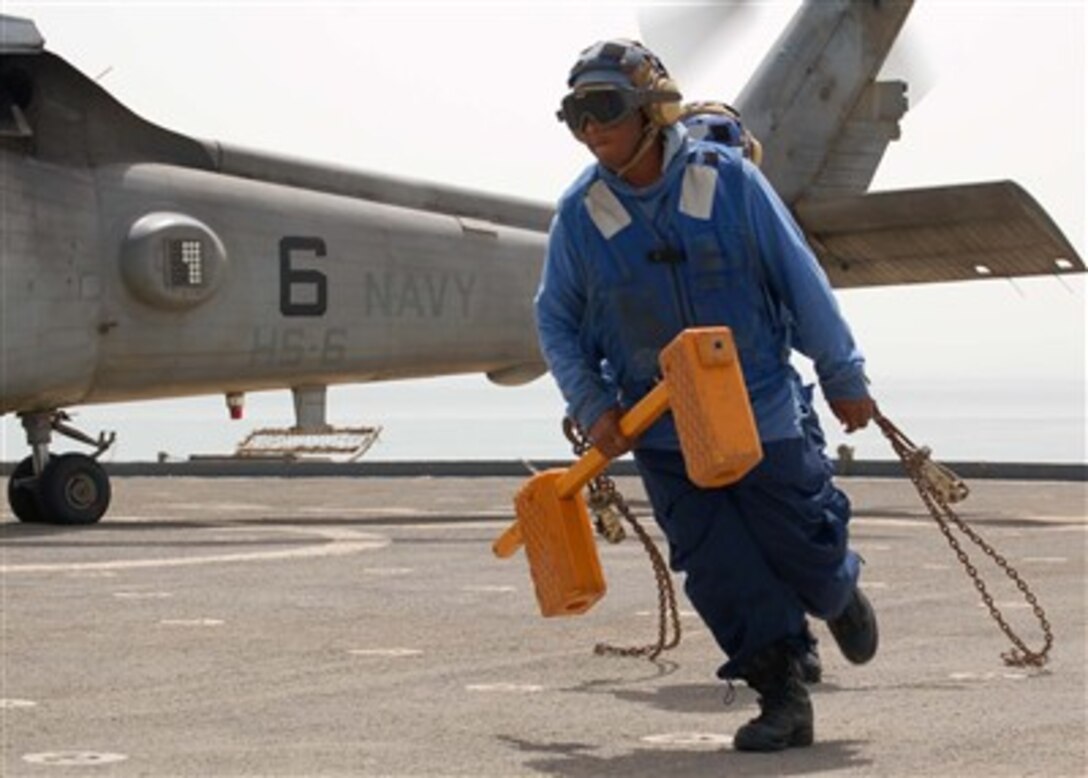 U.S. Navy Petty Officer 3rd Class Dontay Jones removes chocks from a Desert Hawk helicopter on the flight deck of the dock landing ship USS Rushmore (LSD 47) while under way in the Persian Gulf on July 19, 2007.  