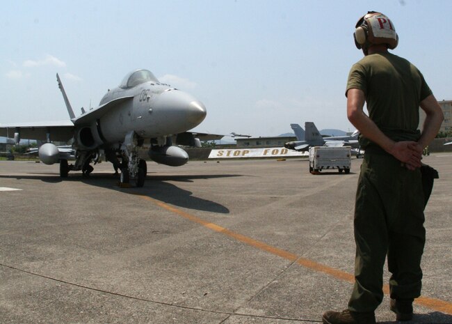 Cpl. Ryan W. Bales, Marine Fighter Attack Squadron 314 plane captain and a native of Tulsa, Okla., stands by as an F/A18 prepares for take-off July 14. During their deployment, VMFA-314 is scheduled to take part in several Far East exercises with the 31st Marine Expeditionary Unit.