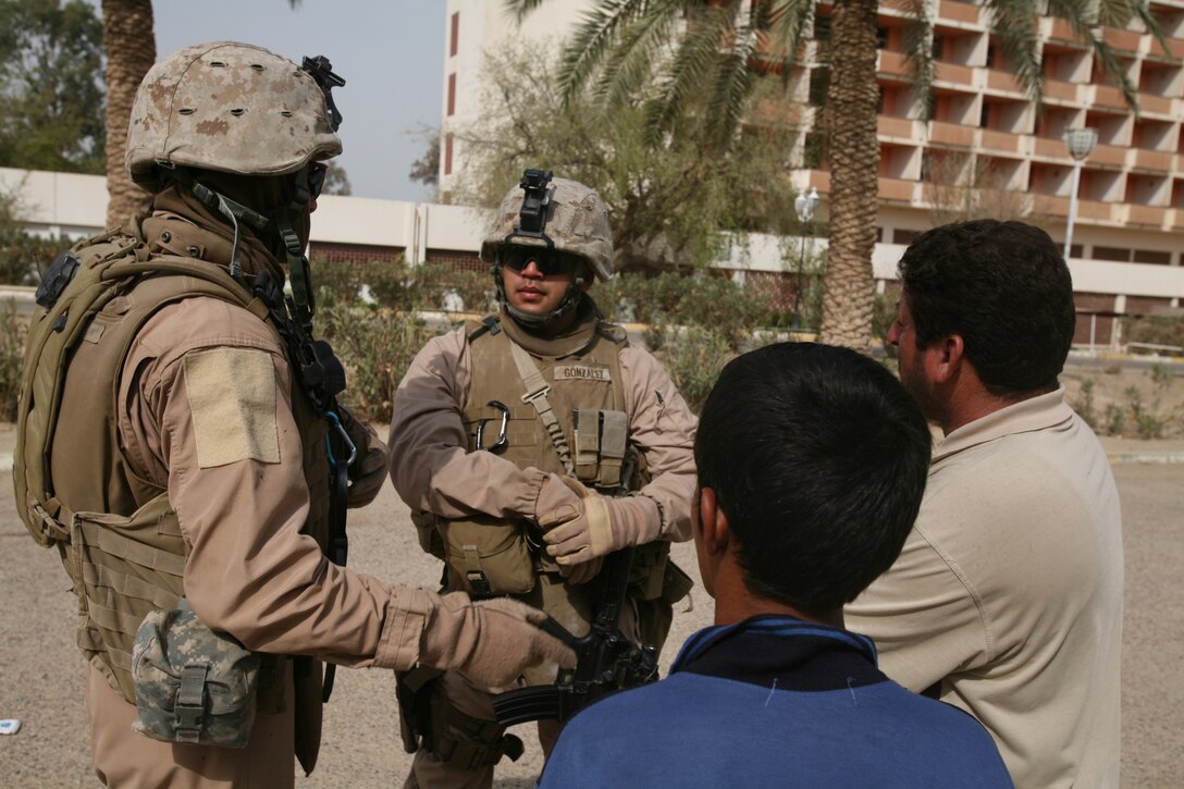 AL TAQADDUM, Iraq (July 25, 2007) ? A child listens as Sgt. Mike R. Gonzalez speaks with a local Iraqi through an interpreter at Al Madinah as Siyahiyah July 25.  Marines with 1st Battalion, 11th Marine Regiment frequently patrol the nearby area referred to as ?Tourist Town? in defense of Camp Taqaddum.  Gonzalez is a patrol leader and Modesto, Calif., native with the battalion.