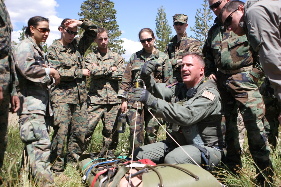 Navy Petty Officer 1st Class Brad Kuflak, medical technician, from Naval Air Station Fallon, Nev., assist students in a litter hoisting during their final exercise in the summer Mountain Medicine Course at the Marine Corps Mountain Warfare Training Center July 25.