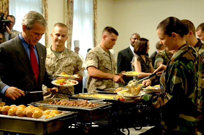 President George Bush prepares a plate of food with military members at the Charleston Club Tuesday. (U.S. Air Force Photo/Airman 1st Class Nicholas Pilch)