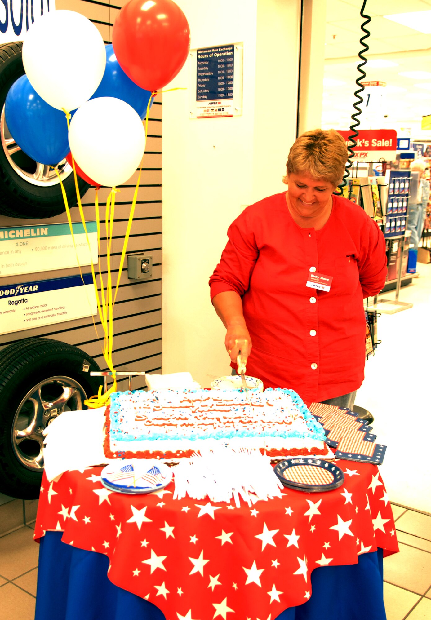 WHITEMAN AIR FORCE BASE, Mo. -- Becky Stover, Whiteman Base Exchange manager, cuts the Army and Air Force Exchange Services’ 112th anniversary cake at the Whiteman BX July 25. (U.S. Air Force photo/Airman 1st Class Stephen Linch)