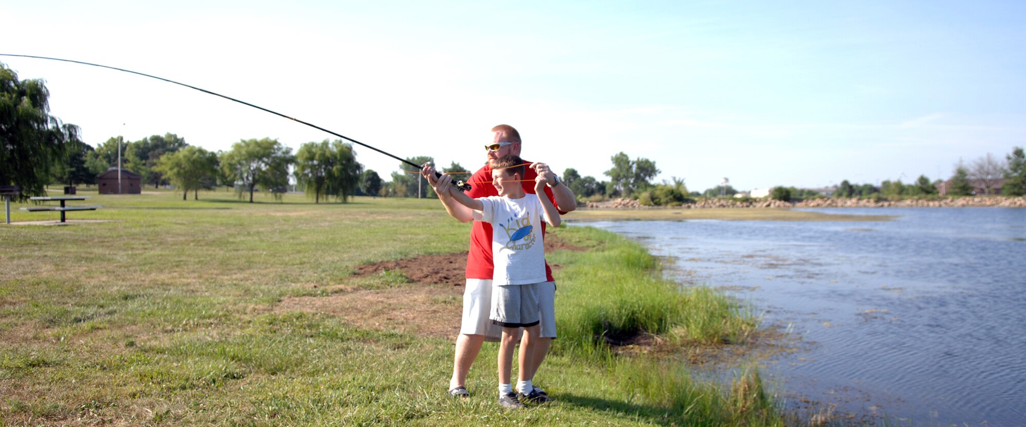 WHITEMAN AIR FORCE BASE, Mo. -- Jerry Davenport helps Matthew Gangemella, son of Master Sgt. Gregg Gangemella, 509th Aircraft Maintenance Squadron, and Sharon Gangemella, 509th SVS, casts a fly line into Ike Skelton Lake during a youth fishing class July 24. For other events check www.whitemanservices.com (U.S. Air Force photo/Airman 1st Class Stephen Linch)
. 
