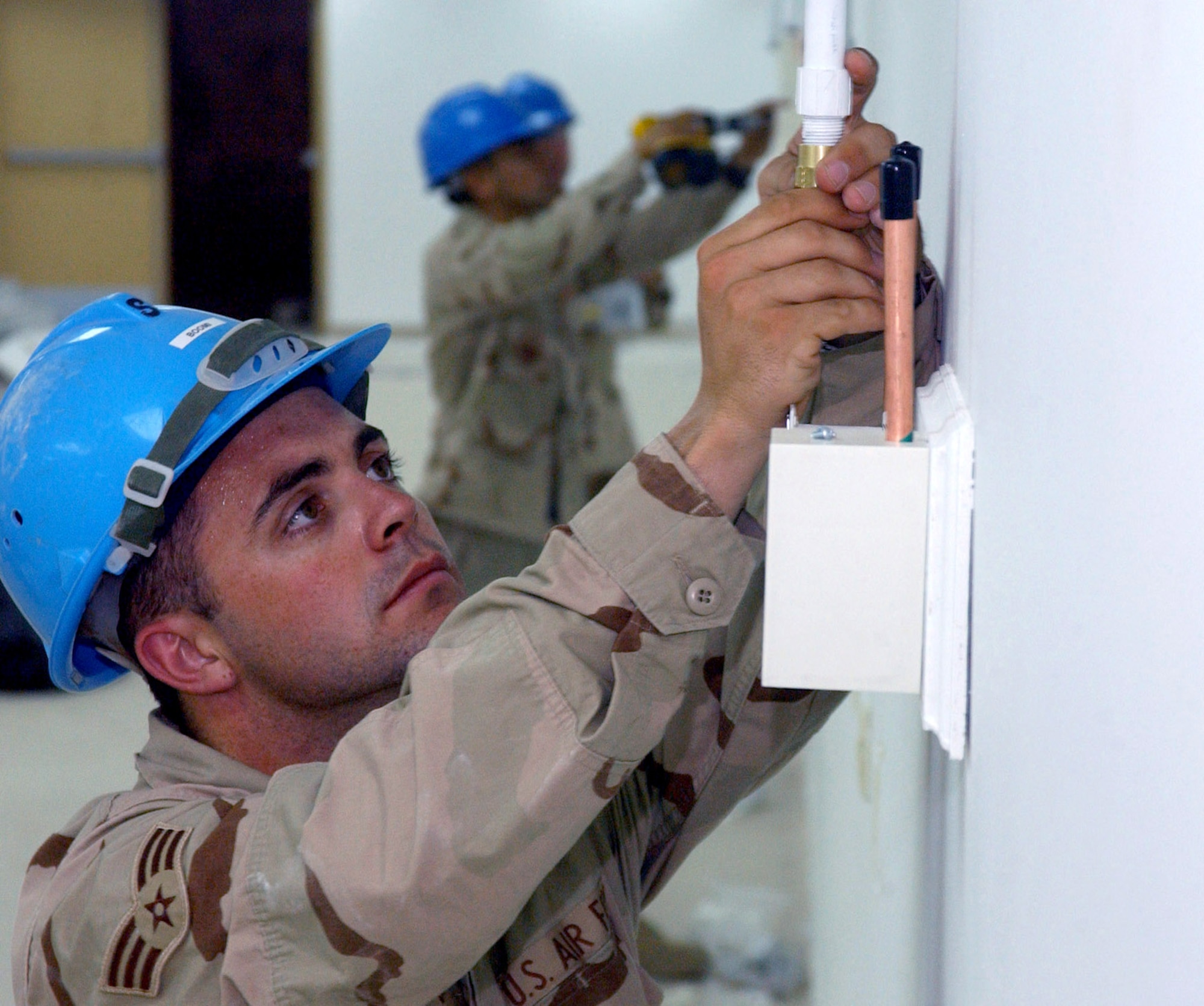 Senior Airman Scott Hatch connects a vacuum line from the main system to the vacuum outlet box on the wall of the ward in the new Air Force Theater Hospital being built at Balad Air Base, Iraq.  The new hospital is replacing the old tent structure.  Airman Hatch is deployed from the 81st Medical Support Squadron at at Keesler Air Force Base, Miss.  (U.S. Air Force photo/1st Lt. Shannon Collins) 