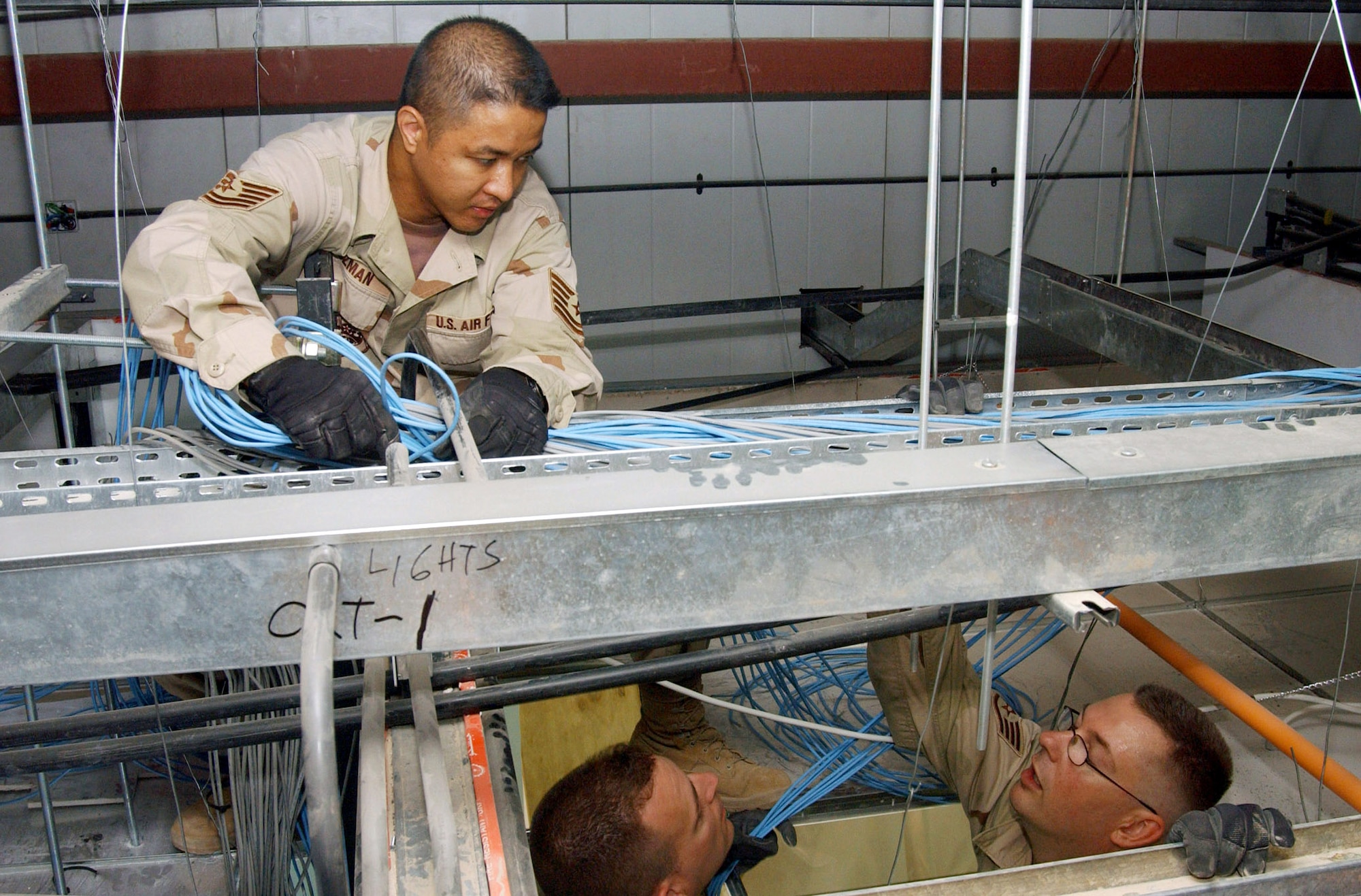 Tech. Sgt. Gary Guzman, Tech. Sgt. Jeremy Harding and Staff Sgt. Robert Luna string data communication cables in the new Air Force Theater Hospital being built at Balad Air Base, Iraq.  The new hospital is replacing the old tent structure.  Throughout the transition, Airmen have pulled more than 50,000 feet of computer cables; set up computers, phones and paging systems and more. The new hospital is scheduled to open Aug. 3.  The three NCOs are with the 332nd Expeditionary Medical Support Squadron.  (U.S. Air Force photo/1st Lt. Shannon Collins)