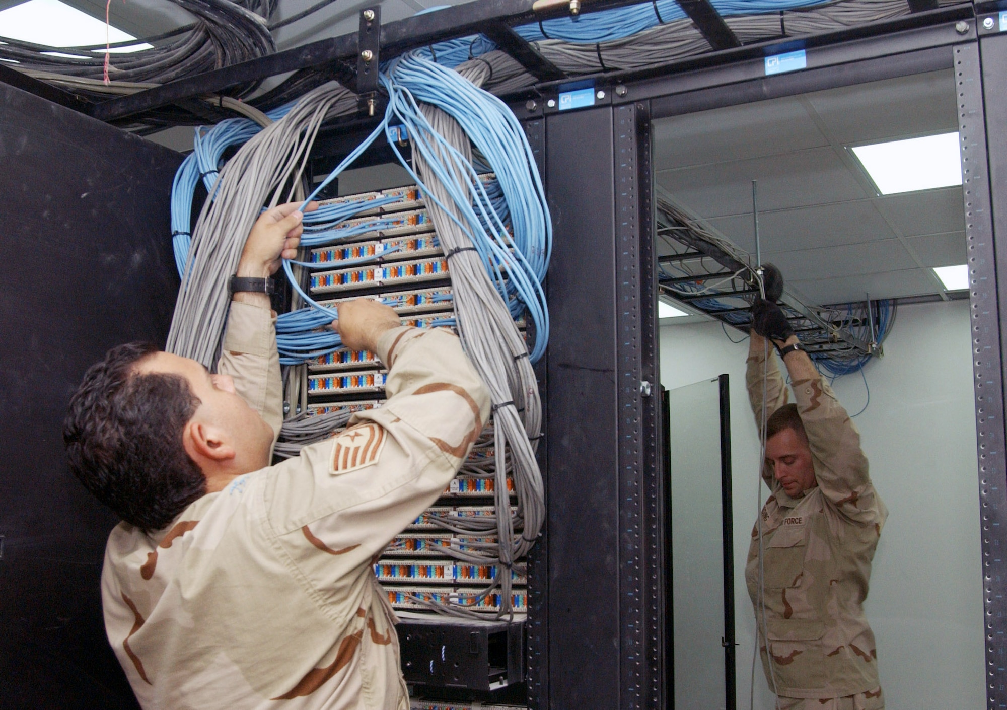 Tech. Sgts. Chris Valadez and Jeremy Harding connect data communication cables into a hub in the new Air Force Theater Hospital being built at Balad Air Base, Iraq.  The new hospital is replacing the old tent structure.  Throughout the transition, Airmen have pulled more than 50,000 feet of computer cables; set up computers, phones and paging systems and more. The new hospital is scheduled to open Aug. 3.  The NCOs are with the 332nd Expeditionary Medical Support Squadron.  (U.S. Air Force photo/1st Lt. Shannon Collins)