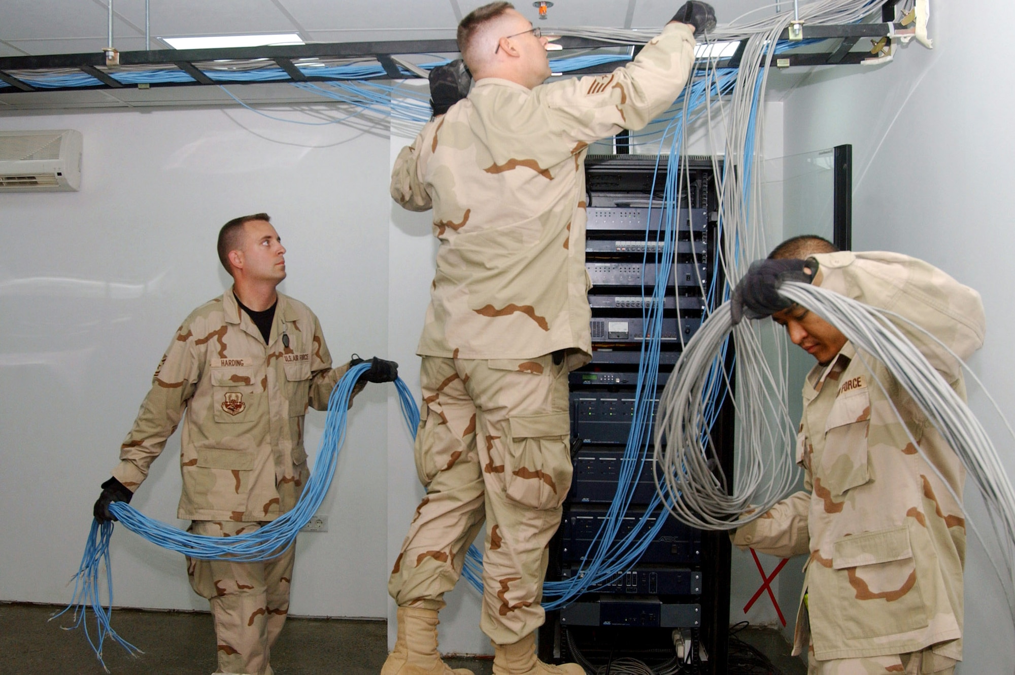 Tech. Sgt. Jeremy Harding, Staff Sgt. Robert Luna and Tech. Sgt. Gary Guzman string data communication cables in the new Air Force Theater Hospital being built at Balad Air Base, Iraq.  The new hospital is replacing the old tent structure.  Throughout the transition, Airmen have pulled more than 50,000 feet of computer cables; set up computers, phones and paging systems and more. The new hospital is scheduled to open Aug. 3.  The three NCOs are with the 332nd Expeditionary Medical Support Squadron.  (U.S. Air Force photo/1st Lt. Shannon Collins)