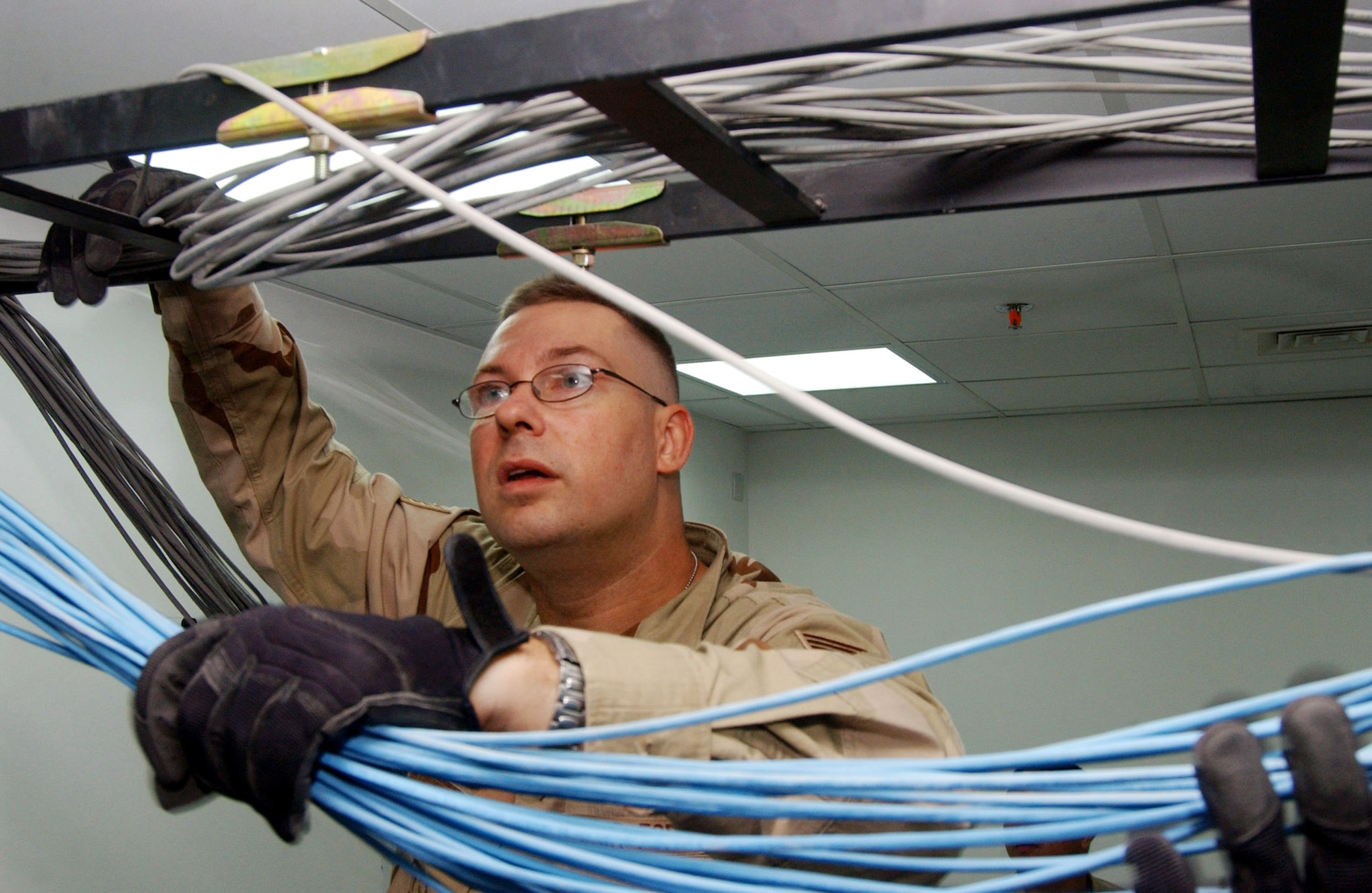Staff Sgt. Robert Luna strings data communication cables in the new Air Force Theater Hospital being built at Balad Air Base, Iraq.  The new hospital is replacing the old tent structure.  Throughout the transition, Airmen have pulled more than 50,000 feet of computer cables; set up computers, phones and paging systems and more. The new hospital is scheduled to open Aug. 3.  Sergeant Luna is with the 332nd Expeditionary Medical Support Squadron.  (U.S. Air Force photo/1st Lt. Shannon Collins)