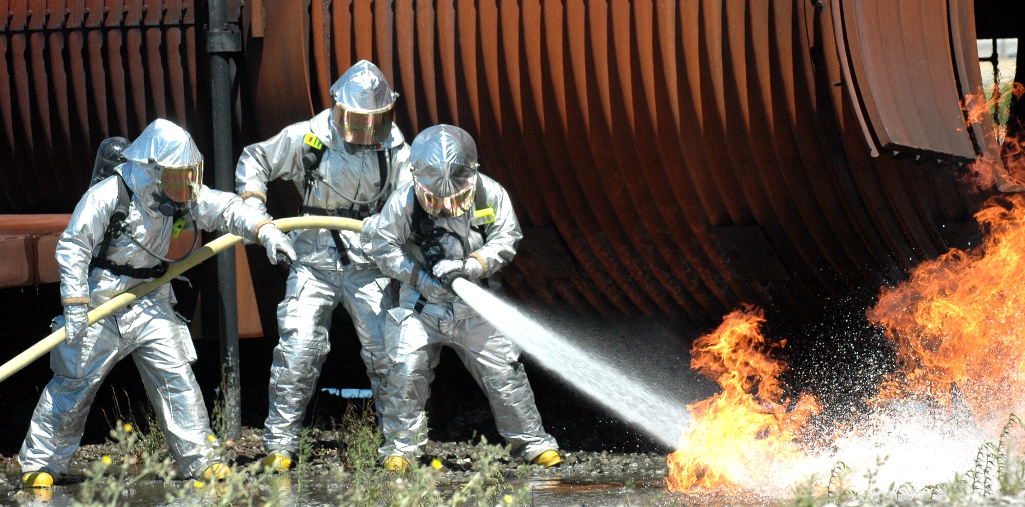Travis firefighters hose down flames outside of aircraft mock-up July 19. The mock-up is equipped with propane gas nozzles installed in and around it to create flames. (U.S. Air Force photo/Staff Sgt. Matthew McGovern)