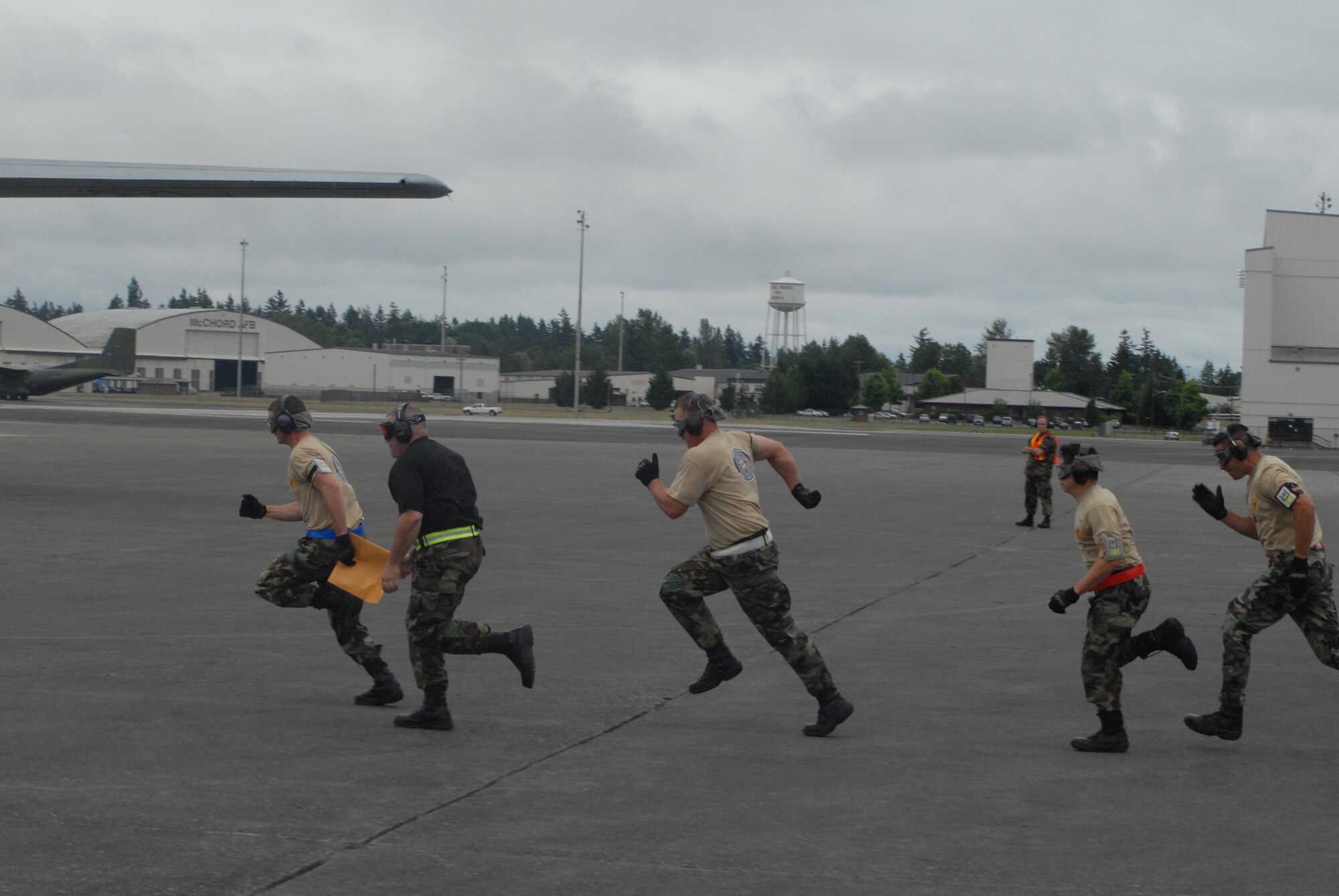 Members of the 2007 Pope Rodeo aerial port team run out to Pope’s C-130 to meet with loadmasters during an engine running onload/offload event Monday at McChord Air Force Base, Wash. The event included backing a humvee with trailor onto the aircraft followed by transferring a palletized load via K-loader and then offloading in reverse order within 12 minutes.. (U.S. Air Force photo/Staff Sgt. Jon Ladue)