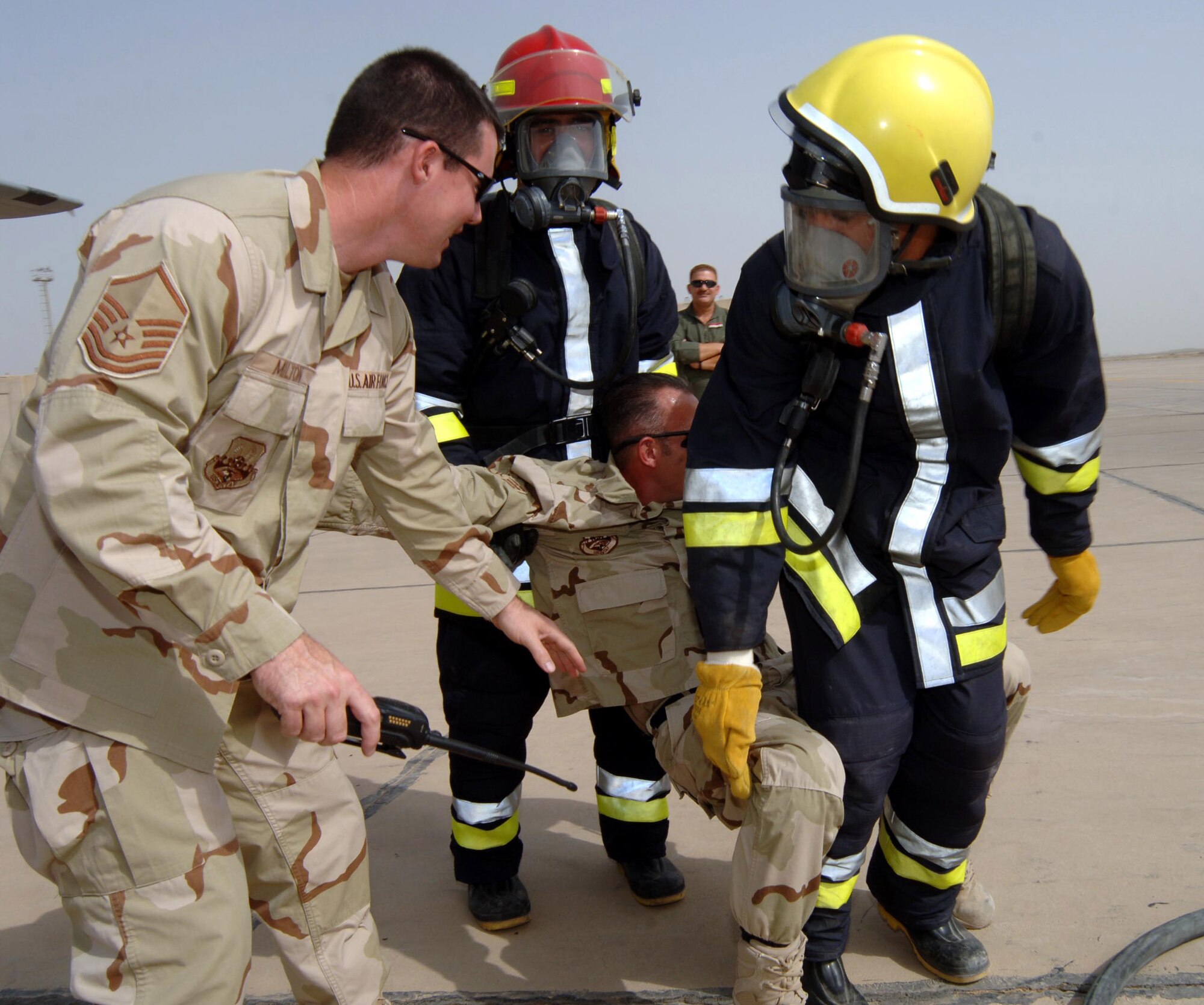 Master Sgt. Craig Milton observes firefighters from the Iraqi air force remove Staff Sgt. Vance Vansteel from an Iraqi C-130 flight deck July 9 at New Al-Muthana Air Base, Iraq. Sergeant Vansteel represented an unconscious pilot during a simulated aircraft fire. The exercise trained Iraqis to respond to an aircraft fire by shutting down engines and removing an unconscious pilot. U.S. Airmen set up the scenario and guided them through the process. Sergeants Milton and Vansteel are firefighters with the 447th Expeditionary Civil Engineer Squadron. (U.S. Air Force photo/Tech. Sgt. Russell Wicke) 
