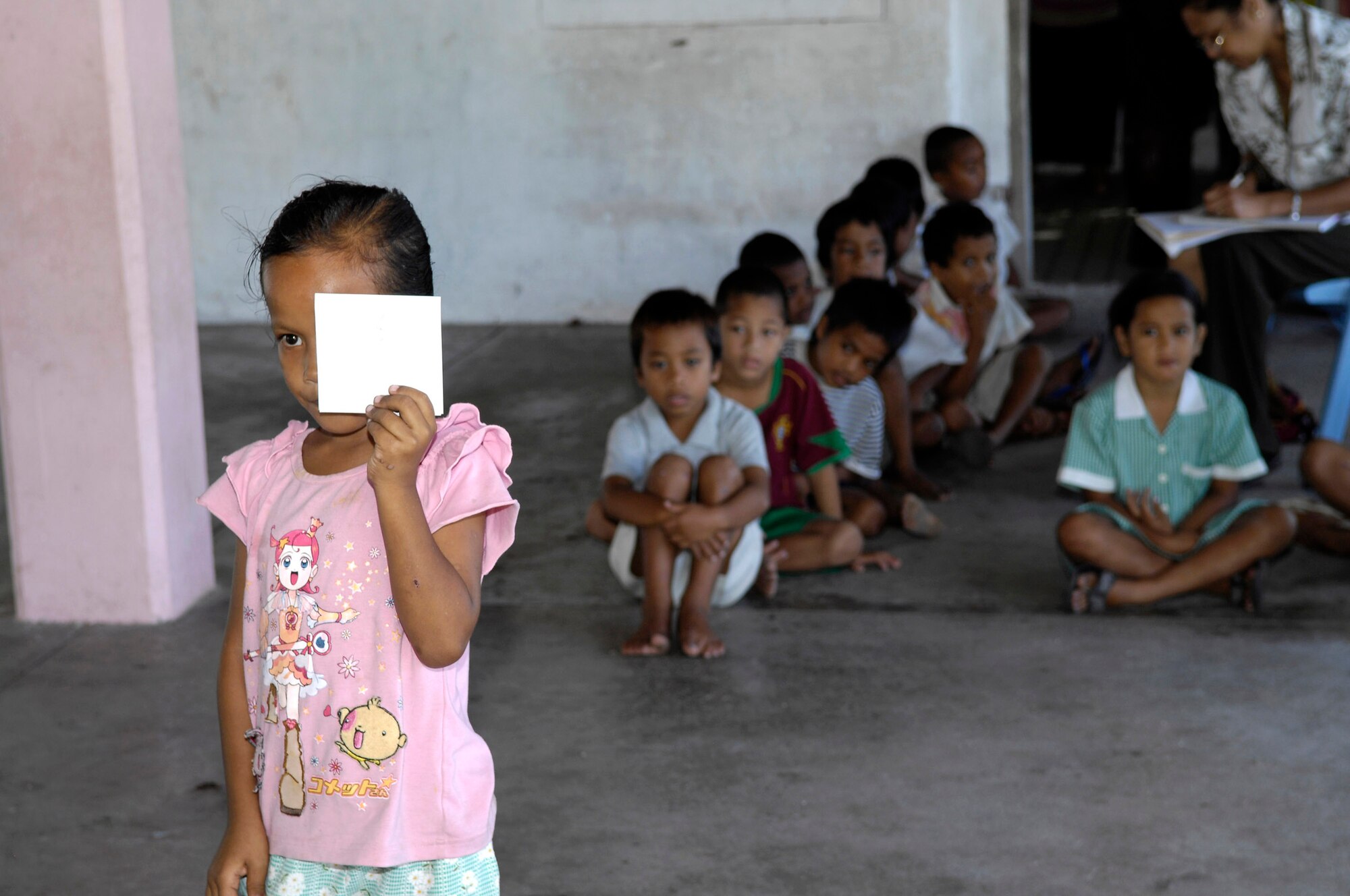 A first grader covers one eye while reading the vision chart to test her vision July 22 on the island of Nauru. A 12-person, joint-force U.S. Pacific Command team of medical professionals are deployed to the island July 21 through 28 to provide training and assistance to the island's medical professionals. (U.S. Air Force photo/Tech. Sgt. Chris Vadnais)
