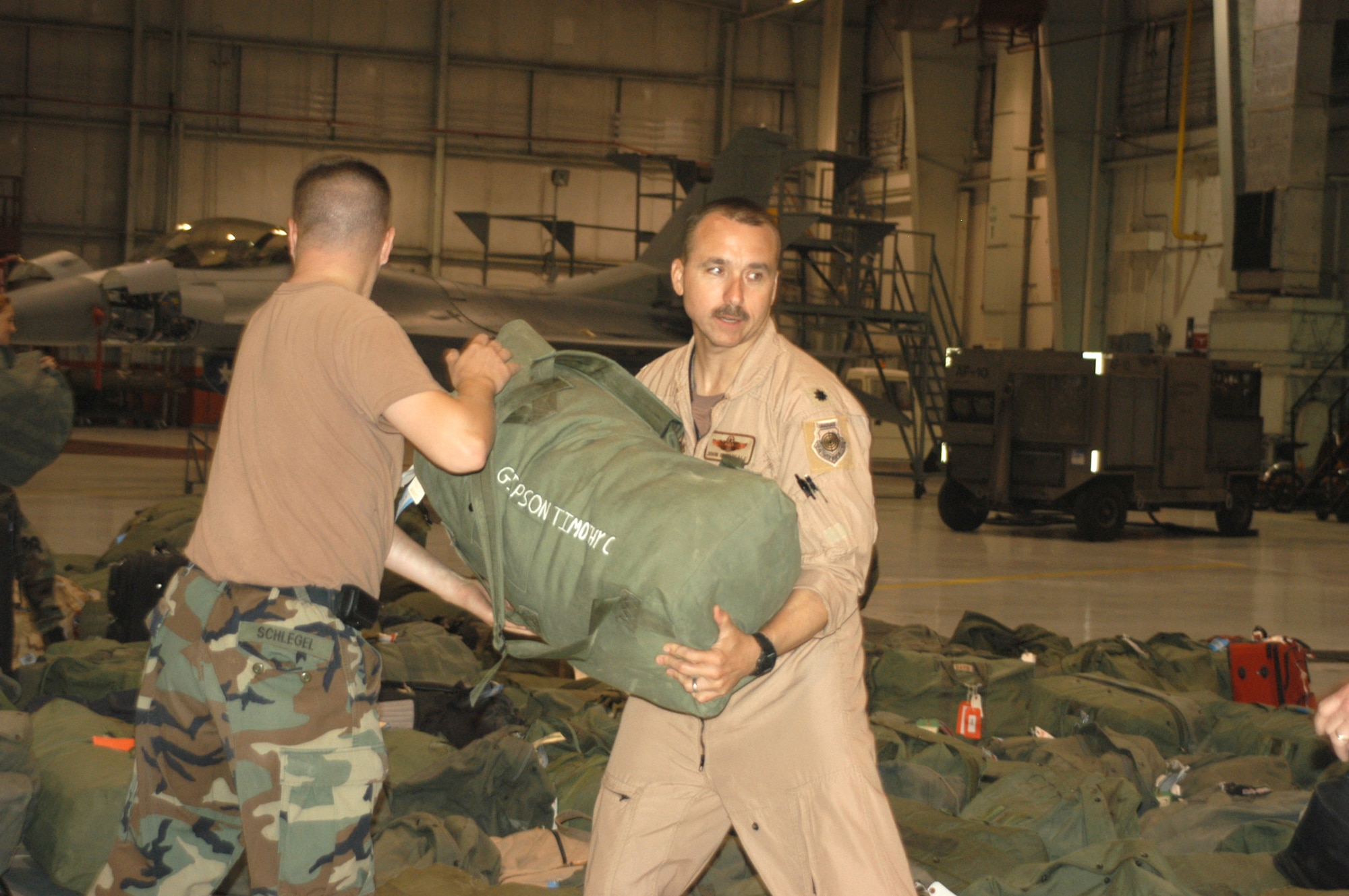 Lt. Col. John Breazeale, 457th Fighter Squadron F-16 pilot, lends a hand unloading bags to help get everyone home sooner after their deployment to Balad Air Base, Iraq. Nearly 200 Air Force Reservists from the 301st Fighter Wing out of the Naval Air Station Joint Reserve Base Fort Worth, Texas, deployed in support of Operation Iraqi Freedom this Spring. (U.S. Air Force Photo/Tech. Sgt. Julie Briden-Garcia)