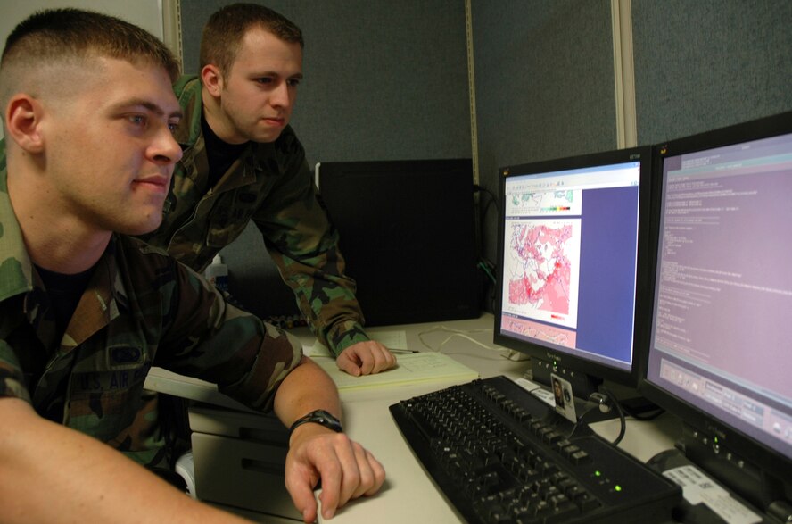 Front to back: Senior Airman Ben Smeland, a software applications technician with the Air Force Weather Agency's 2nd System Operations Squadron at Offutt AFB, Neb., and Senior Airman Russell Pyle, also a software applications technician, work on streamlining code for the Gridded Analysis and Display System used by troops world wide. Photo by G. A. Volb.