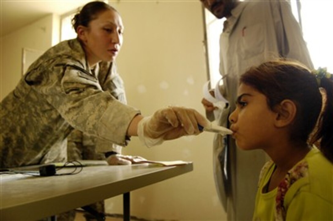 U.S. Army Sgt. Cecilia Garcia (left) assists a patient during a combined medical operation conducted by soldiers from 3rd Squadron, 1st Cavalry Regiment, 3rd Brigade Combat Team, 3rd Infantry Division on July 16, 2007, in Hollandia, Iraq.  Garcia is assigned to Charlie Company, 203rd Brigade Support Battalion.  