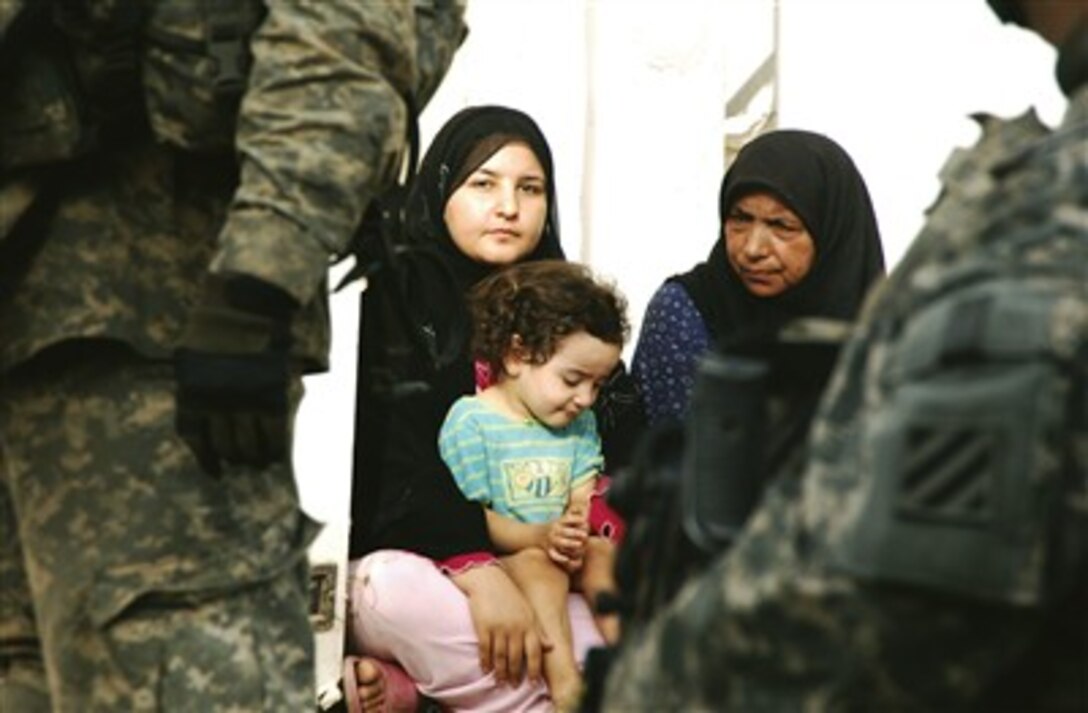 U.S. Army soldiers from 1st Platoon, Alpha Company, 1st Battalion, 30th Infantry Regiment, provide a protective posture over an Iraqi mother and her child during a possible incoming mortar attack in Al Bu'aytha, Iraq, July 20, 2007. 