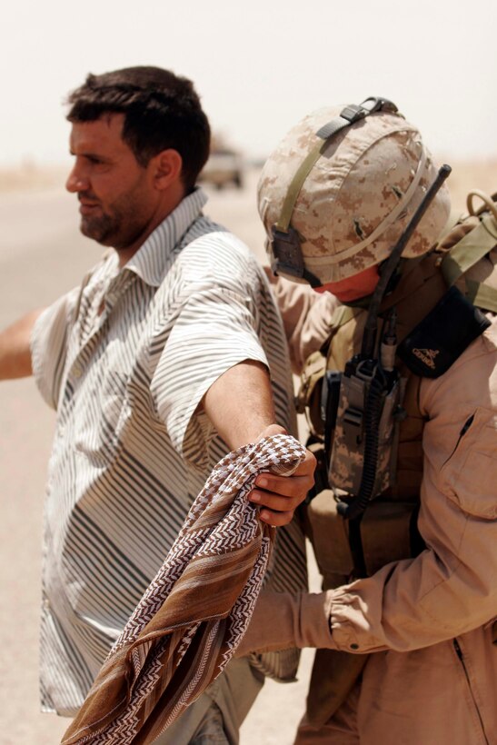AL TAQADDUM, Iraq (July 26, 2007) - Sgt. Cody R. Bigham, a patrol leader with 1st Battalion, 11th Marine Regiment, searches a local national who was stopped on the roadside of a nearby route during a security patrol conducted near here.  1st Bn., 11th Marines is deployed here with Multi National Forces-West in support of Operation Iraqi Freedom in the Al Anbar province of Iraq to develop Iraqi Security Forces, facilitate the development of official rule of law through democratic reforms, and continue the development of a market based economy centered on Iraqi reconstruction.