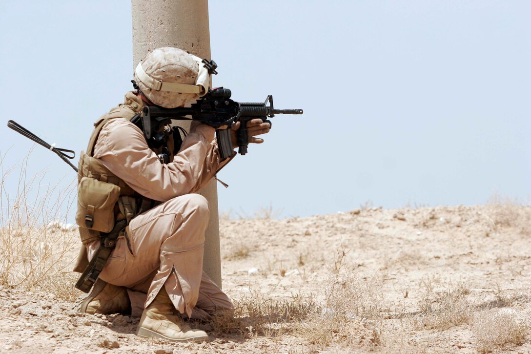 AL TAQADDUM, Iraq (July 26, 2007) - 2nd Lt. Matthew Farmwald, 1st Battalion, 11th Marine Regiment, gets cover and searches the area behind a pole on the roadside of a nearby route during a security patrol being conducted by 1/11. 1st Bn., 11th Marines is deployed here with Multi National Forces-West in support of Operation Iraqi Freedom in the Al Anbar province of Iraq to develop Iraqi Security Forces, facilitate the development of official rule of law through democratic reforms, and continue the development of a market based economy centered on Iraqi reconstruction.