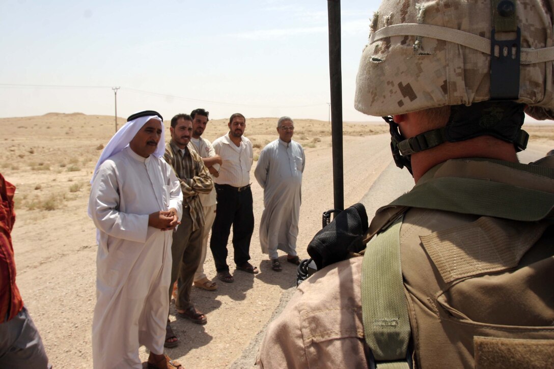 AL TAQADDUM, Iraq (July 26, 2007) - Sgt. Cody R. Bigham, a patrol leader with 1st Battalion, 11th Marine Regiment, listens to complaints of local nationals whose vehicle was stopped on the roadside of a nearby route during a security patrol conducted here by 1/11. 1st Bn., 11th Marines is deployed here with Multi National Forces-West in support of Operation Iraqi Freedom in the Al Anbar province of Iraq to develop Iraqi Security Forces, facilitate the development of official rule of law through democratic reforms, and continue the development of a market based economy centered on Iraqi reconstruction.