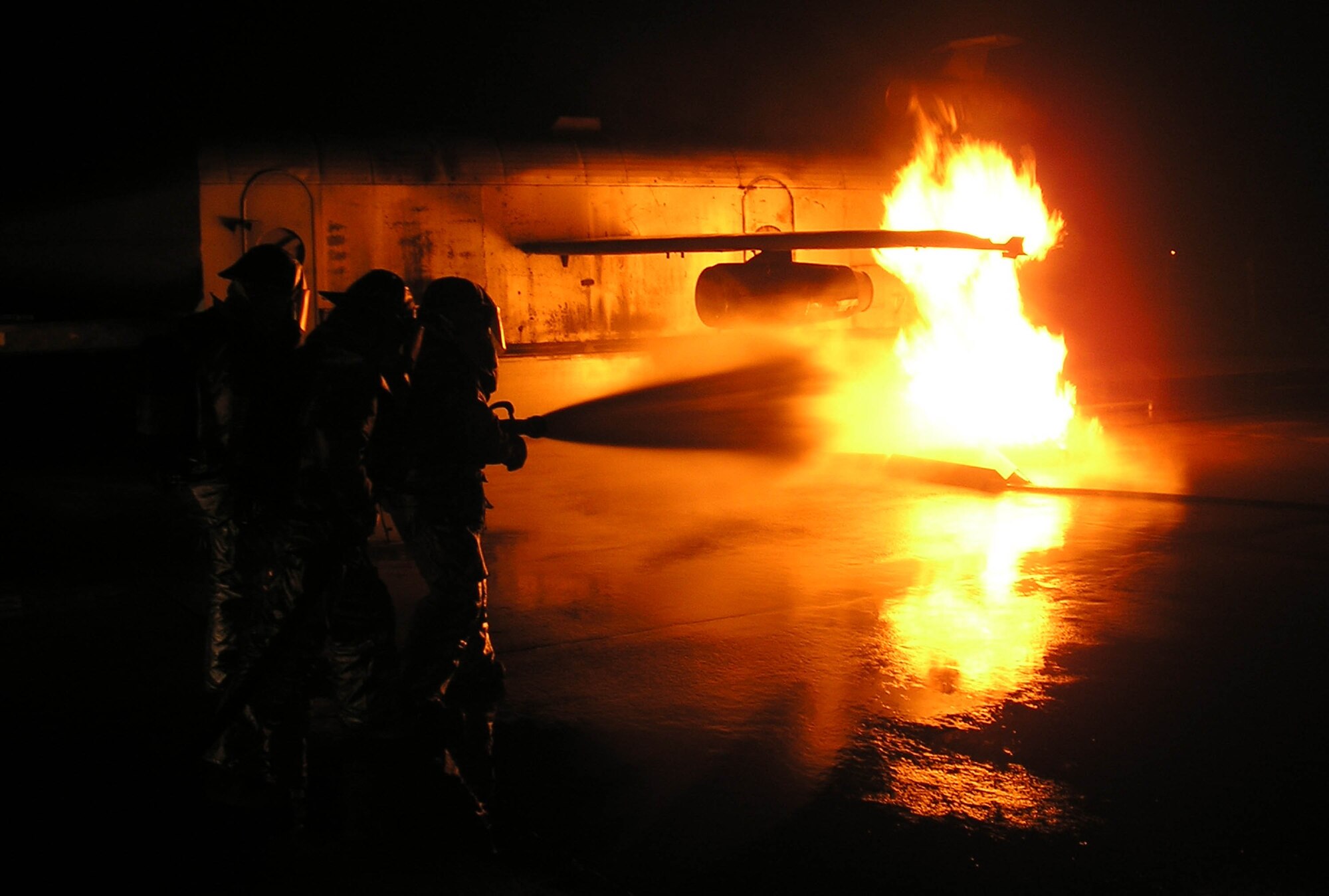 KUNSAN AIR BASE, Republic of Korea -- Firefighters Staff Sgt. David Call and Airmen 1st Class Christopher Osborne and Mark Brandt attack a simulated engine fire head on during a training scenario July 26. The realistic training, conducted during the quarterly Seventh Air Force Peninsula Combat Employment Readiness Exercise July 23 - 27, helps firefighters here hone their emergency response skills in the event of an aircraft fire. Each firefighter is assigned to the 8th Civil Engineer Squadron fire and emergency services flight. (U.S. Air Force photo/Master Sgt. Victor Davis) 