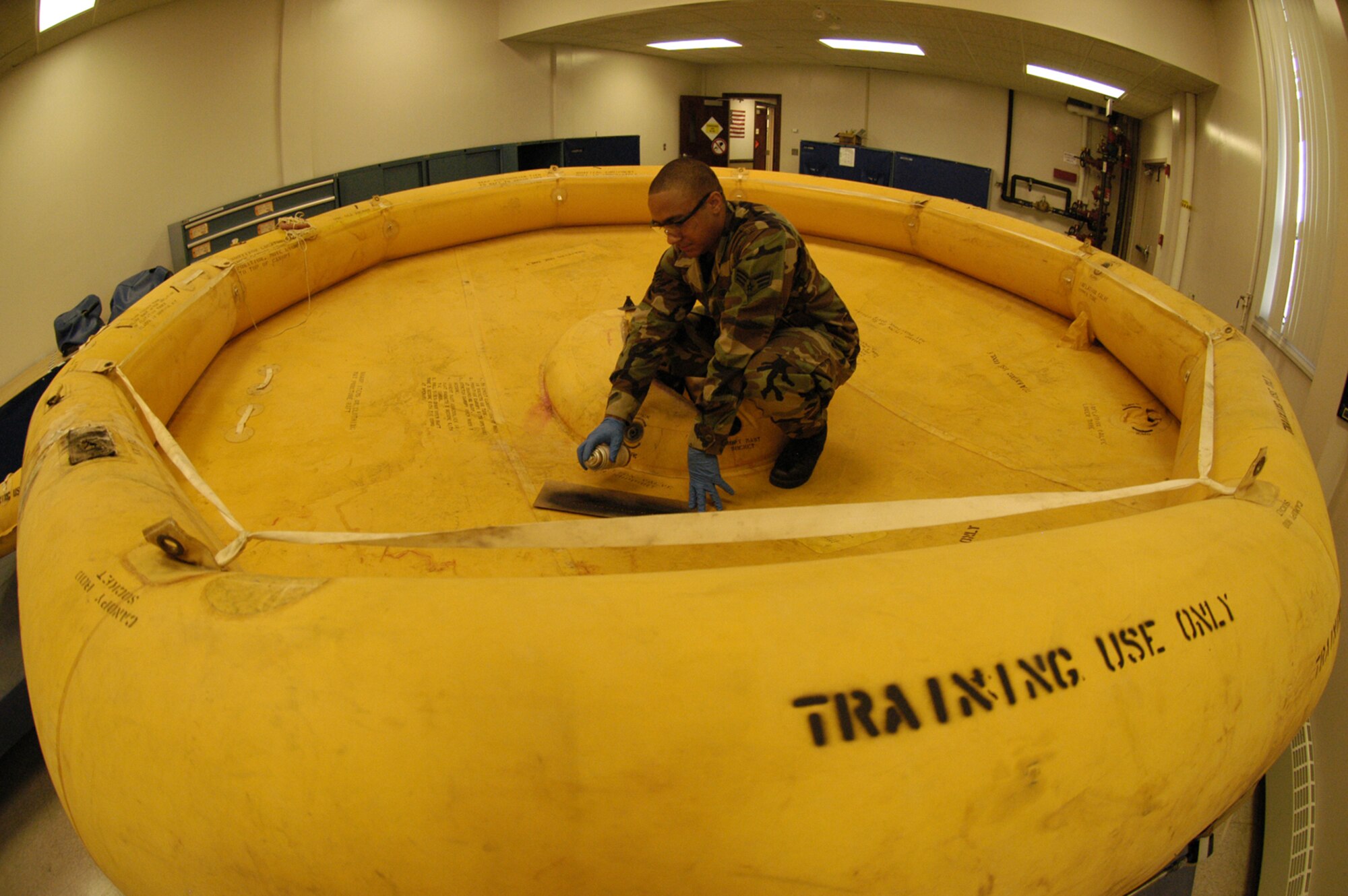 Senior Airman Mark Kennedy, 436th Operation Support Squadron aircrew flight equipment technician, stencils ‘training use only’ on AN inflated 25-person life raft. The former life support technician said the raft will be used by Survival Evasion Resistance Escape teams to train aircrew on survival scenarios. (U.S. Air Force photo/Airman Shen-Chia Chu)