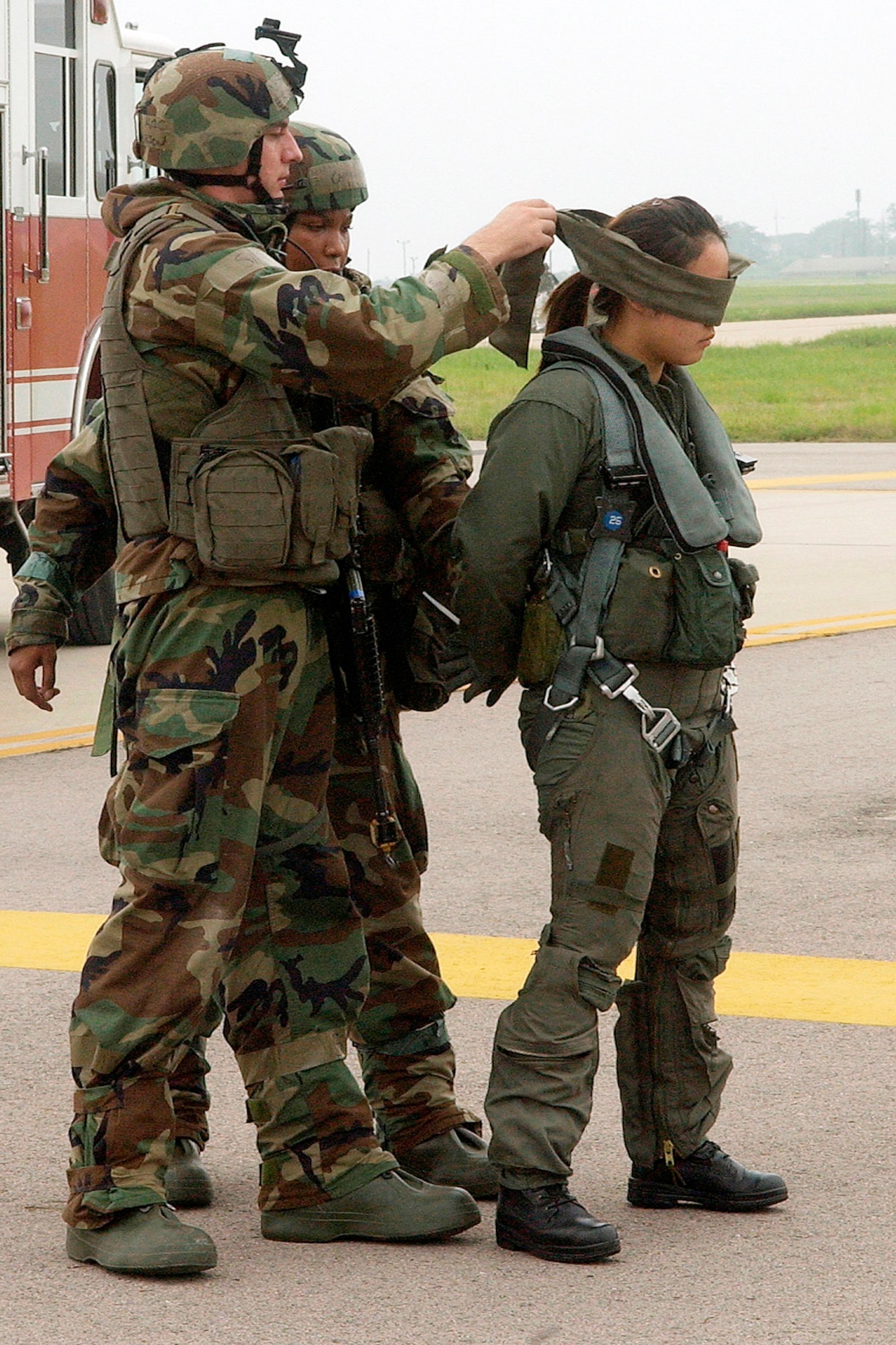 Airmen 1st Class Erik Halvorson and Caprell Edwards blindfold an unidentified individual on the flightline July 26 at Kunsan Air Base, South Korea. The scenario is part of the week-long 7th Air Force Peninsula-Wide Combat Employment Readiness Exercise taking place July 23 through 27. The exercise tests the ability of Air Force fighter wings to properly defend South Korea through the use of airpower. Airmen Halvorson and Edwards are assigned to the 8th Security Forces Squadron. (U.S. Air Force photo/Senior Airman Giang Nguyen) 
