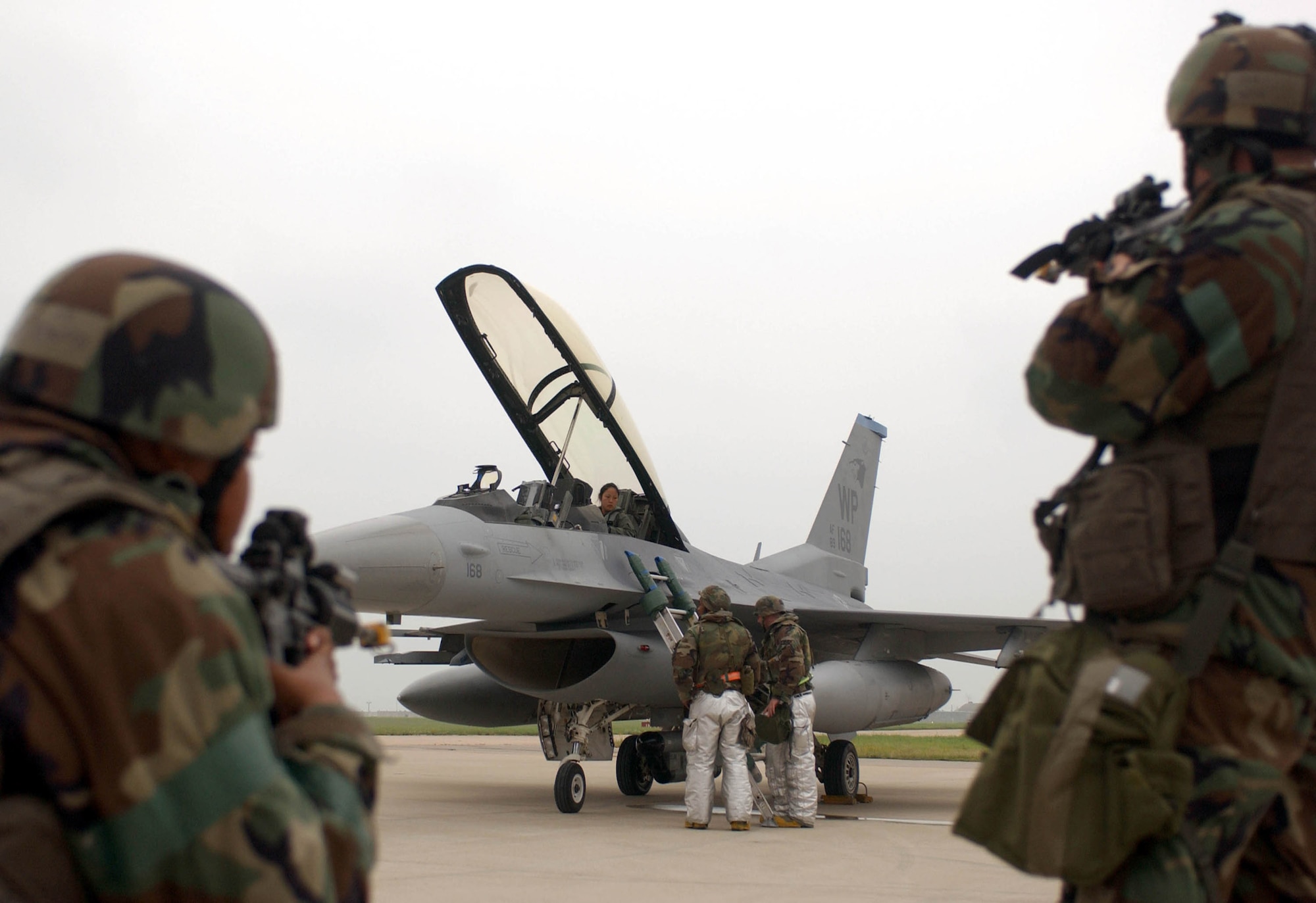Defenders from the 8th Security Forces Squadron provide security as Senior Airmen Lionel James (left) and Preston Walden escort an unidentified individual off the flightline July 26 at Kunsan Air Base, South Korea. The scenario is part of the week-long 7th Air Force Peninsula-Wide Combat Employment Readiness Exercise taking place July 23 through 27. The exercise tests the ability of Air Force fighter wings to properly defend South Korea through the use of airpower. Airmen James and Walden are 8th Civil Engineer Squadron firefighters. (U.S. Air Force photo/Senior Airman Steven R. Doty) 
