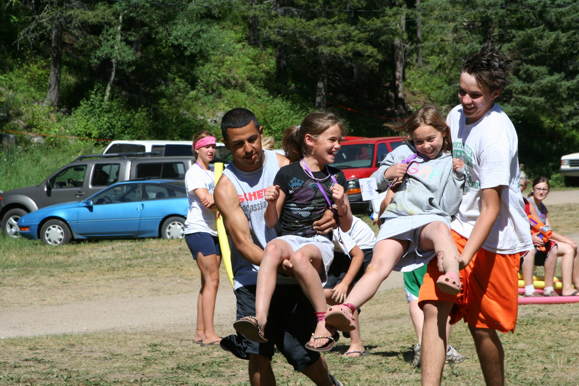 Senior Airman Adrian Ortiz, 341st Mission Support Squadron MPF employments technician, left, helps Ethan Kapp, 15, son of Air National Guardsman, far right, carry two young campers during a three-legged race at Operation Purple Camp July 11. The week-long camp is a nation-wide project that brings together children whose parents are deployed, and gives them coping skills and emotional support. Airman Ortiz is a second-year camp counselor and volunteer. (U.S. Air Force photo / Senior Airman Eydie Sakura)
