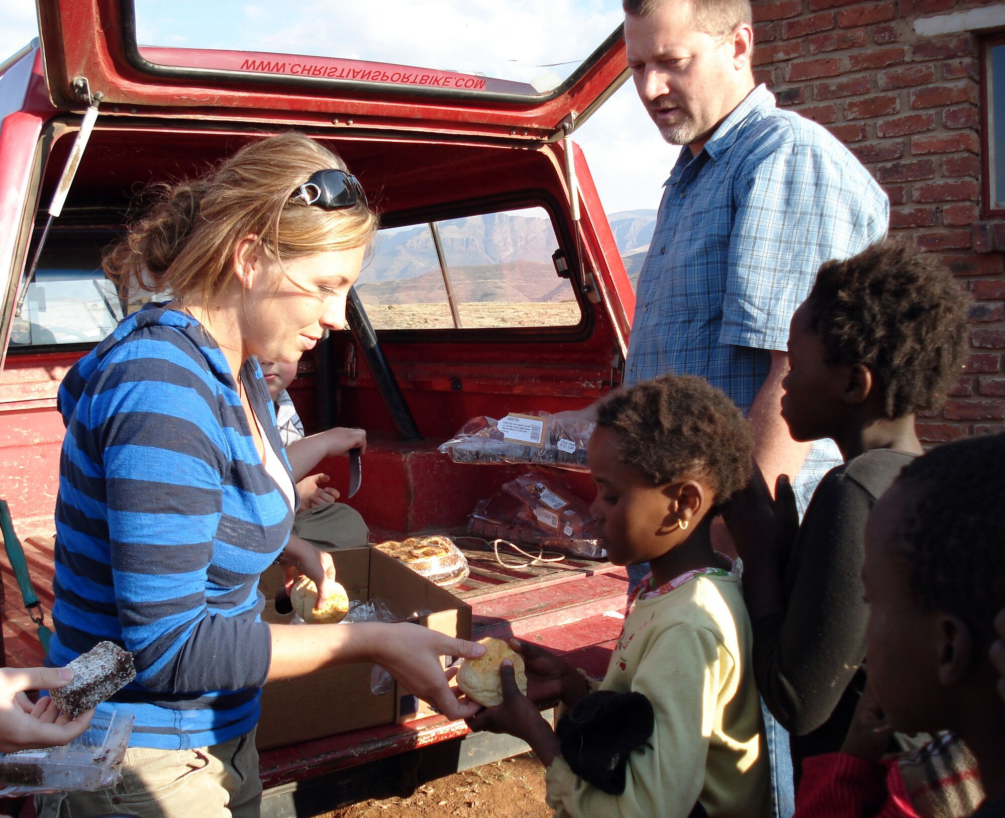 Ms. Kossakoski and Wim Van Rensberg hand out biscuits to the Leratong children on the troop's first day in the village. (Courtesy Photo)