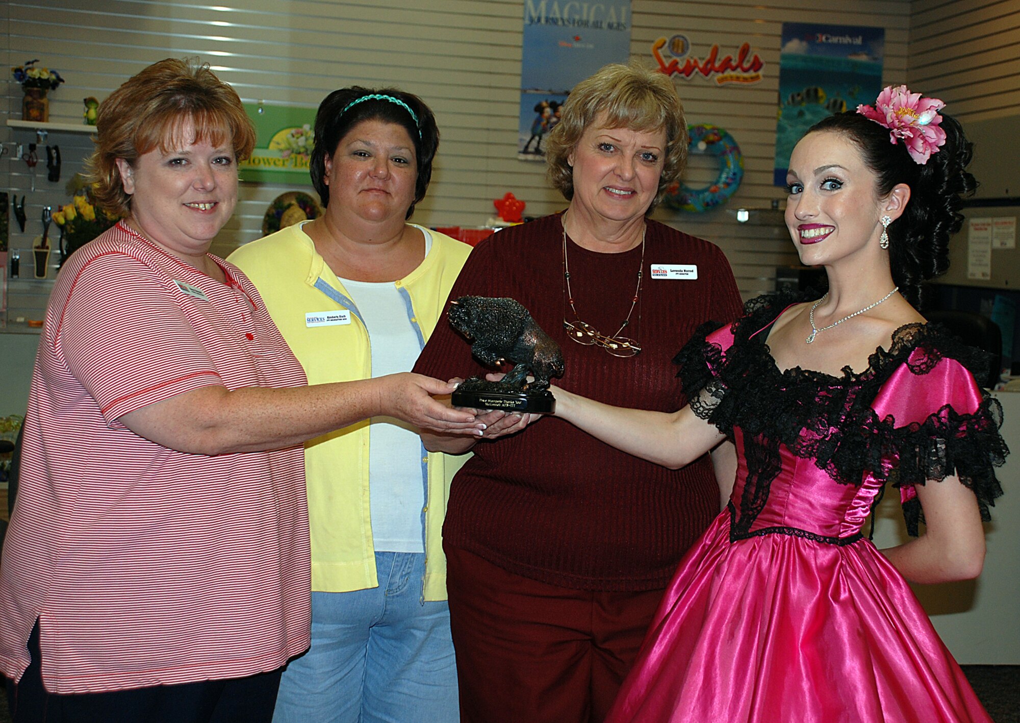 MCCONNELL AIR FORCE BASE, Kan. -- Dana Bennett, Information, Ticket and Tours travel consultant, Kim Staib, ITT specialist, and Lavonda Norrod, ITT director, are presented the bronze “Stampede of the Buffalos” award by Heather McKain, a performer at Dolly Parton’s Dixie Stampede located in Branson, Mo., July 25. The statuette honors the military travel services that ITT brings to active-duty, retired military personnel and their families. “I wanted to express my appreciation to the military bases for all they do for morale and welfare of service families,” said Dolly Parton in a statement accompanying the award. (Photo by Airman 1st Class Jessica Lockoski)