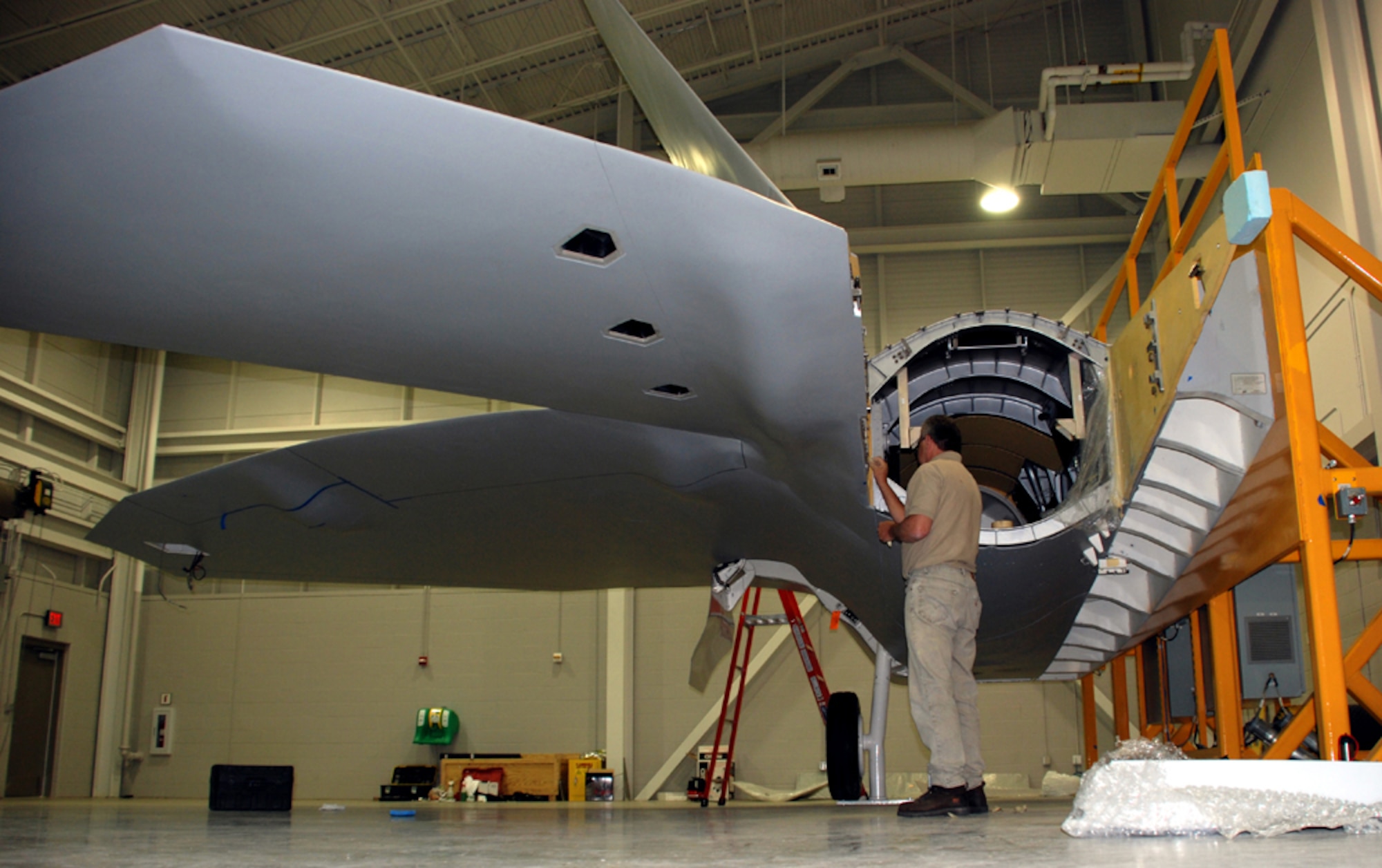 Buddy Cash, a master assembly mechanic with A.I.I. Services, works on the engine section of the first F-22A Raptor fuselage trainer at the new Raptor Maintenance Facility July 20. (U.S. Air Force photo/Airman 1st Class Jacob Corbin)
