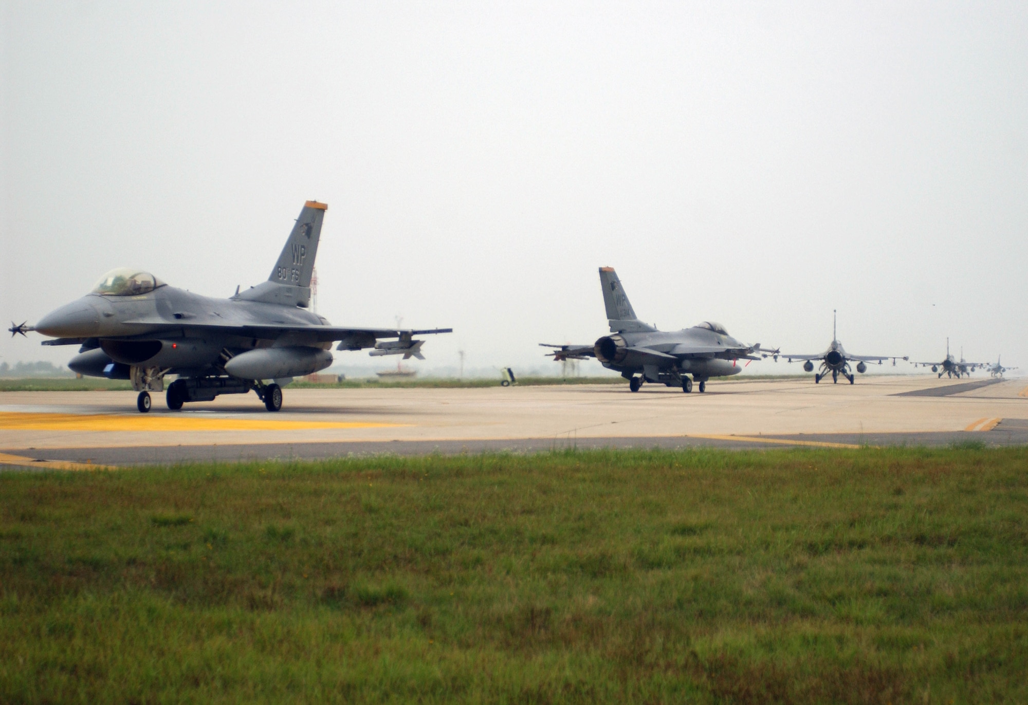 KUNSAN AIR BASE, Republic of Korea --  F-16's from the 35th, 80th and 555th Fighter Squadrons taxi down the runway after returning from a training mission during the Peninsula-Wide Combat Employment Response Exercise July 26. The 555th, "Triple Nickel," has teamed up with the 8th Fighter Wing, "Wolf Pack," during it's four-month deployment here to Kunsan AB. (U.S. Air Force photo/Senior Airman Steven R. Doty)                                            