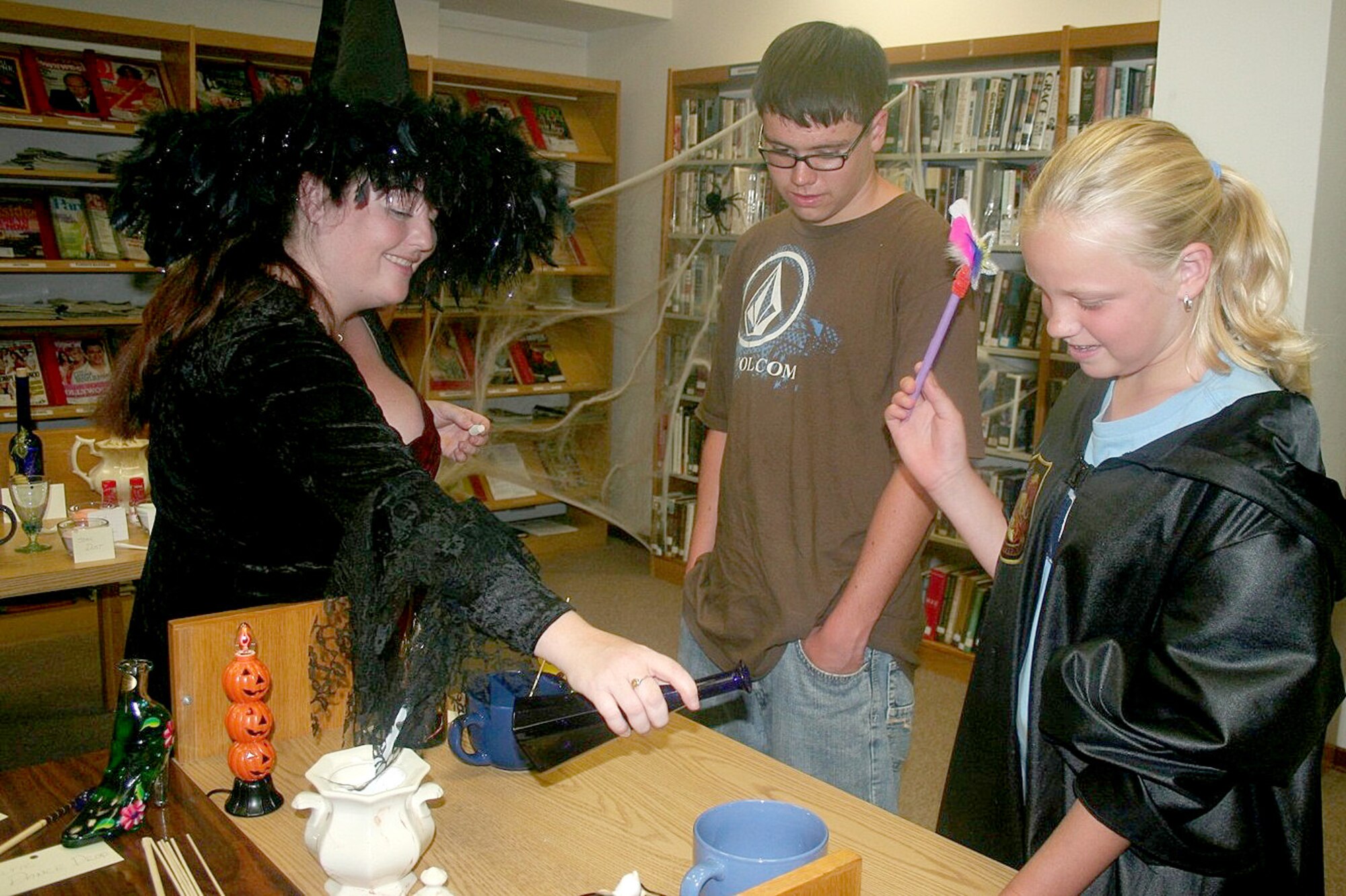 Amber Collins, reference librarian,  pours the final drops for  a ‘magical potion’ into a mixing bowl as attendees look on. Harry Potter night ‘wizards’ created magic wands, creatures and mixed potions while counting down the release of the last book of the series. (Photo by Hugh C. McBride)