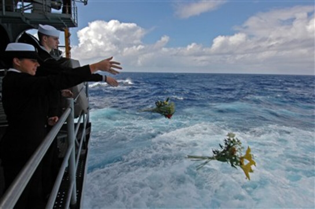 Sailors toss flowers into the sea during the memorial ceremony for the USS Lexington on the fantail of the USS Kitty Hawk, July 25, 2007.  The spot is where the Lexington sunk during the Battle of the Coral Sea May 8, 1942, losing 216 members from its crew. 