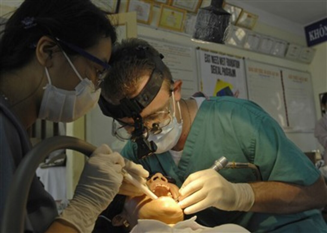 U.S. Navy Lt. Kevin Haveman, along with a dental assistant from the East Meets West Dental Program, cleans the teeth of a Vietnamese woman at the Nai Hiem Dong Medical Station in Da Nang City, Vietnam, on July 24, 2007.  Haveman is with the 3rd Medical Battalion and is deployed in support of Pacific Partnership, a humanitarian assistance mission in Southeast Asia and Oceania that includes specialized medical care and various construction and engineering projects.  