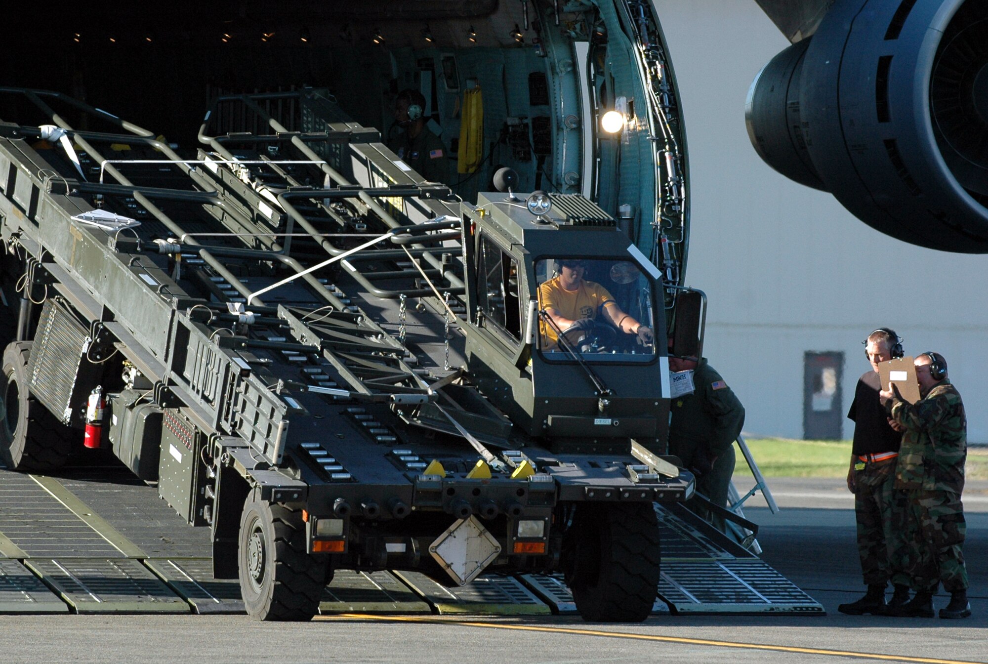 Members of the 60th Aerial Port Squadron Rodeo team unload a K-loader from a C-5 Galaxy during the engine run on/off load July 26 at McChord Air Force Base. During the event the team had to load and unload two vehicles and a trailer in the shortest time possible with no mistakes. (U.S. Air Force photo/Airman 1st Class Kristen Rohrer)