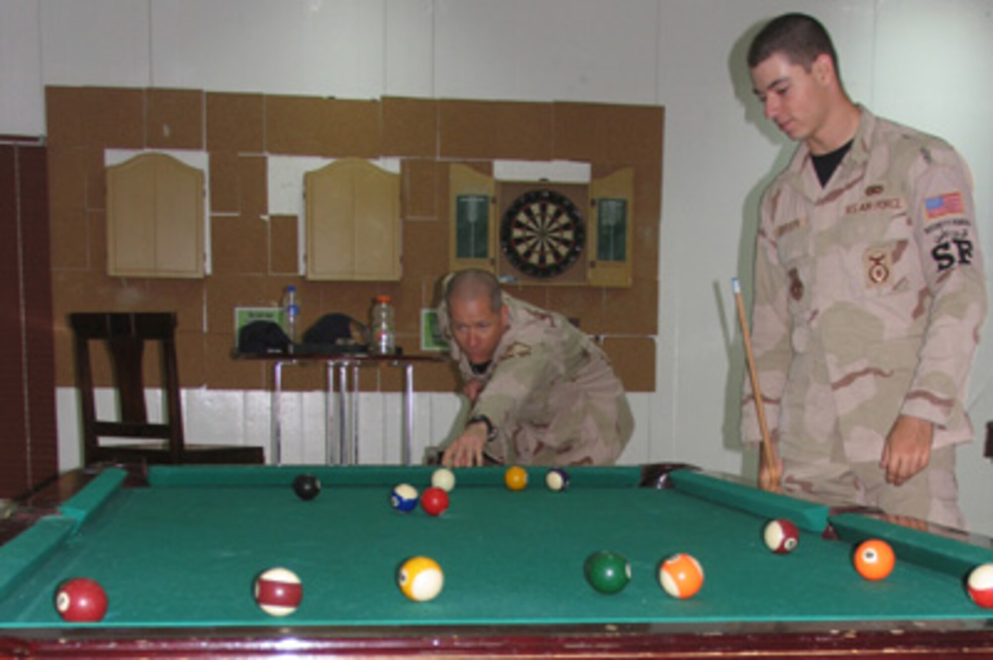 Airman 1st Class Jon Borseth II, looks on as his father, Master Sgt. Jon Borseth, takes his next shot during a game of pool. Sergeant and Airman Borseth take every opportunity to spend quality time together during their deployment to the 386th Air Expeditionary Wing. (Air Force photo by Capt. Shilo Weir) 

