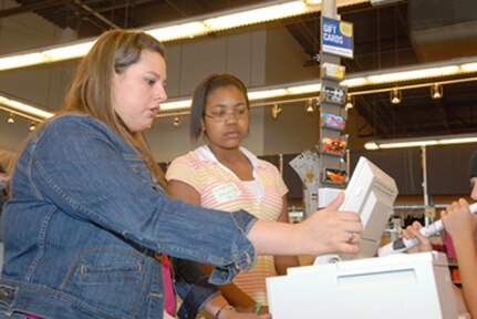An Old Navy employee shows Jasmyn Douglas (right), a student in the Teen Extreme summer program at the Randolph Youth Center, how to operate a cash register during a job-shadowing program Monday at the retail clothing store. (Photo by Rich McFadden)