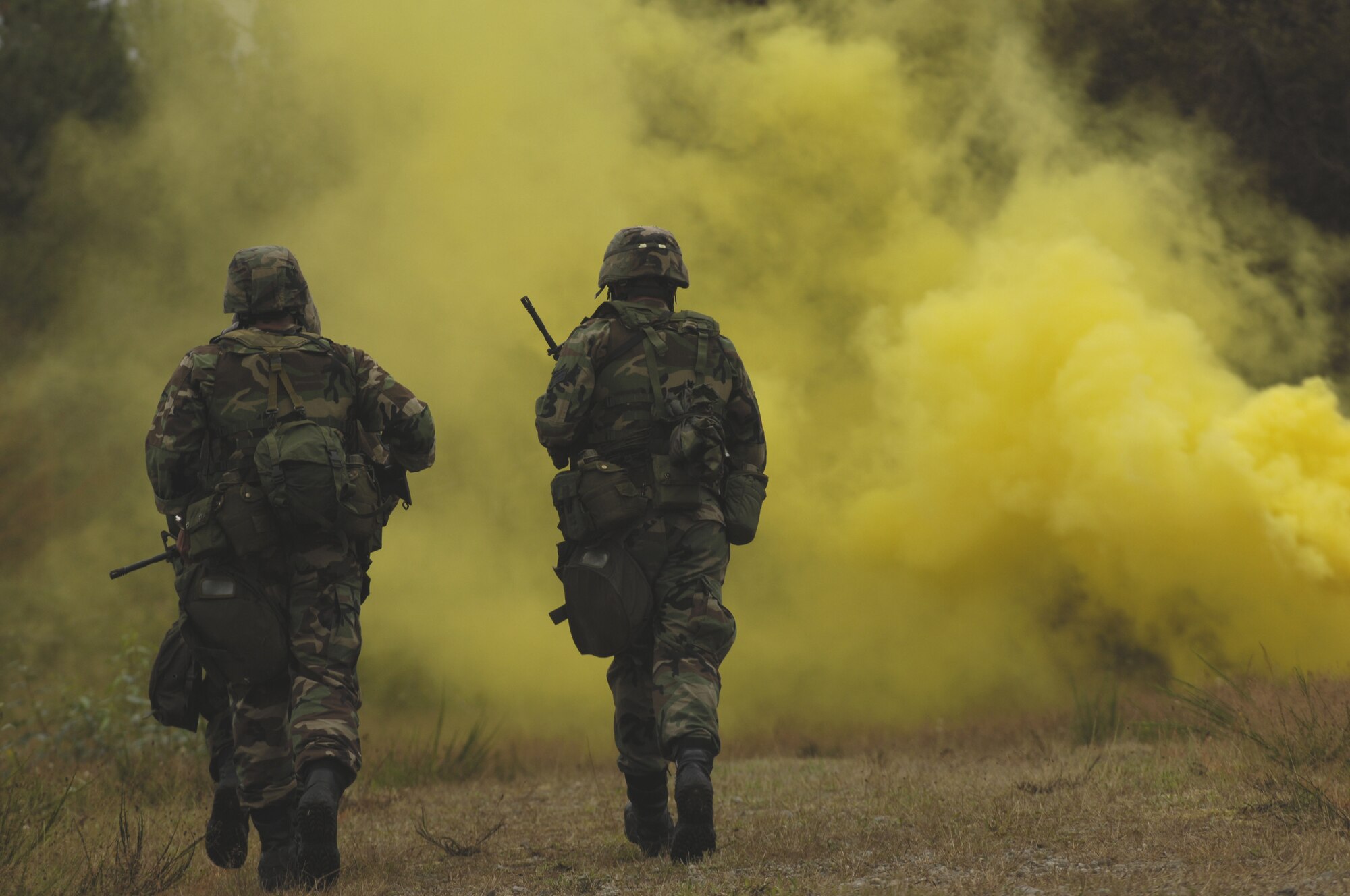 MCCHORD AFB, Wash., -- U.S. Air Force 434th Security Forces Squadron, Grissom Air Reserve Base, Ind., three-man-team run towards yellow smoke, simulating a chemical attack, after donning their gasmasks during Air Mobility Rodeo 2007 weapons competition course set up at range 20, Fort Lewis, Wash., July 23, 2007.  Rodeo 2007, hosted by Air Mobility Command, is a readiness competition of U.S. and international mobility forces.  It focuses on improving warfighting capabilities and support of the Global War on Terrorism. (U.S. Air Force photo by Staff Sgt Ave I. Pele-Sizelove) 