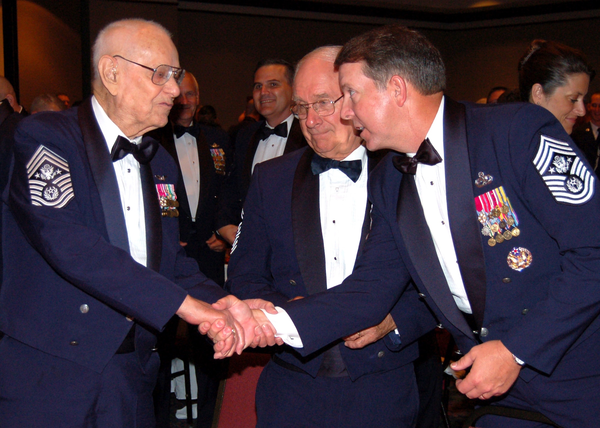 Chief Master Sgt. of the Air Force Rodney J. McKinley (right) shakes hands with Chief Master Sgt. of the Air Force Paul Wesley Airey at the Senior Enlisted Leaders Conference Heritage Dinner July 26 in Montgomery, Ala. Chief Airey was the first Airman to ever hold that position. The eighth Chief Master Sgt. of the Air Force Sam Parrish stands between them. (U.S. Air Force photo/Master Sgt. Lee Roberts) 
