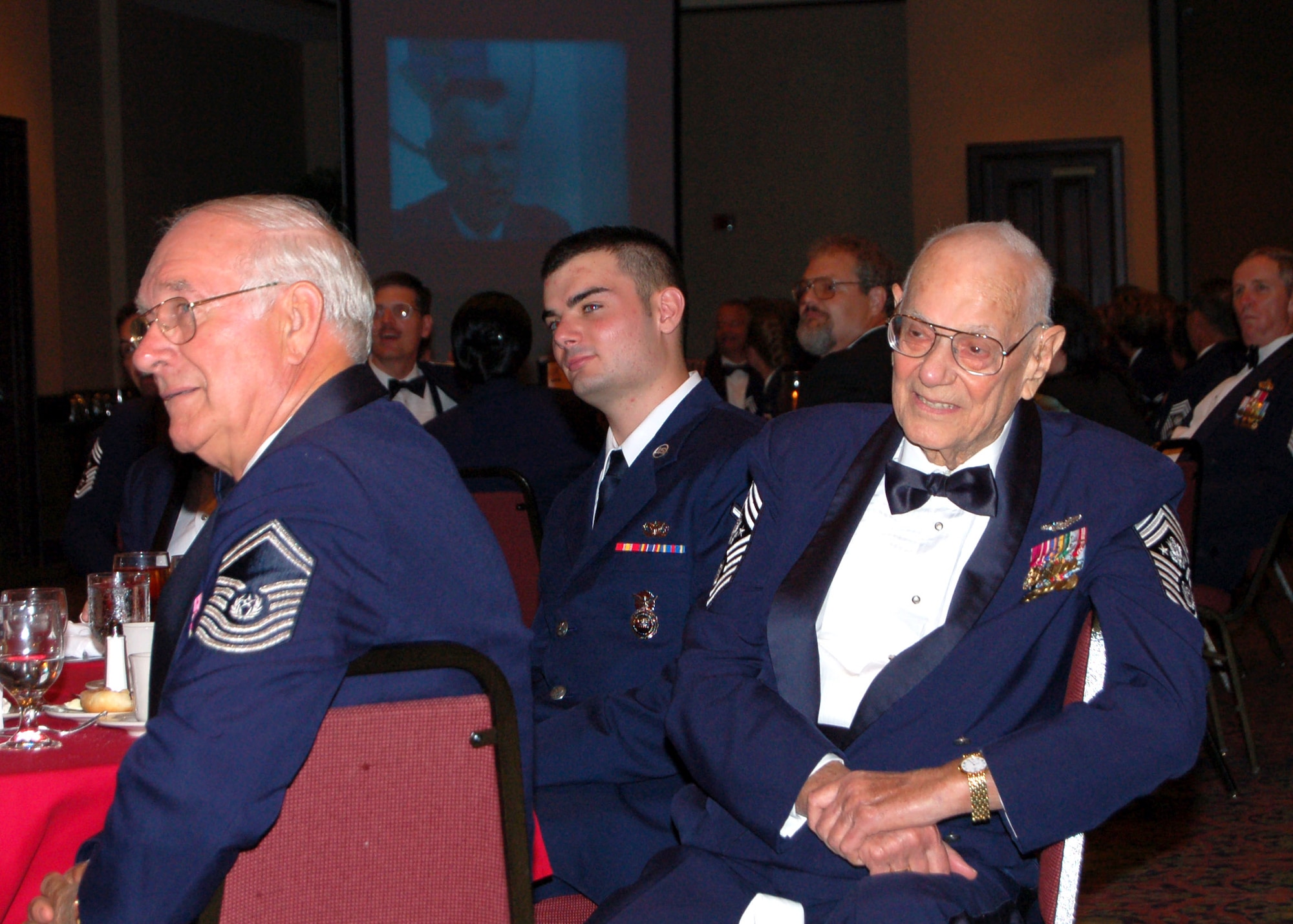 The first Chief Master Sgt. of the Air Force Paul Wesley Airey (right) watches a video in his honor during the Senior Enlisted Leaders Conference Heritage Dinner July 26 in Montgomery, Ala. The eighth Chief Master Sgt. of the Air Force Sam Parish (left) is beside him. (U.S. Air Force photo/Master Sgt. Lee Roberts) 

