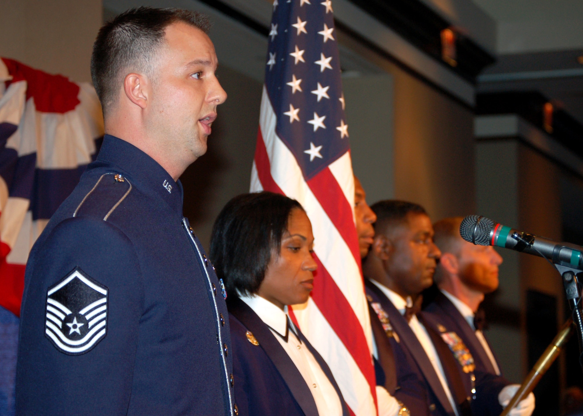 Master Sgt. Bradley Bennett sings the national anthem as the honor guard stood nearby presenting the colors during the Senior Enlisted Leaders Conference Heritage Dinner July 26 in Montgomery, Ala. Sergeant Bennett is assigned to the Air Force Ceremonial Band, and holds the distinction of being the first Air Force member to sing the national anthem for a presidential inauguration. The event was a celebration of the Air Force's 60th Anniversary and the 40th Anniversary of the inception of the Office of the Chief Master Sergeant of the Air Force. (U.S. Air Force photo/Master Sgt. Lee Roberts)
