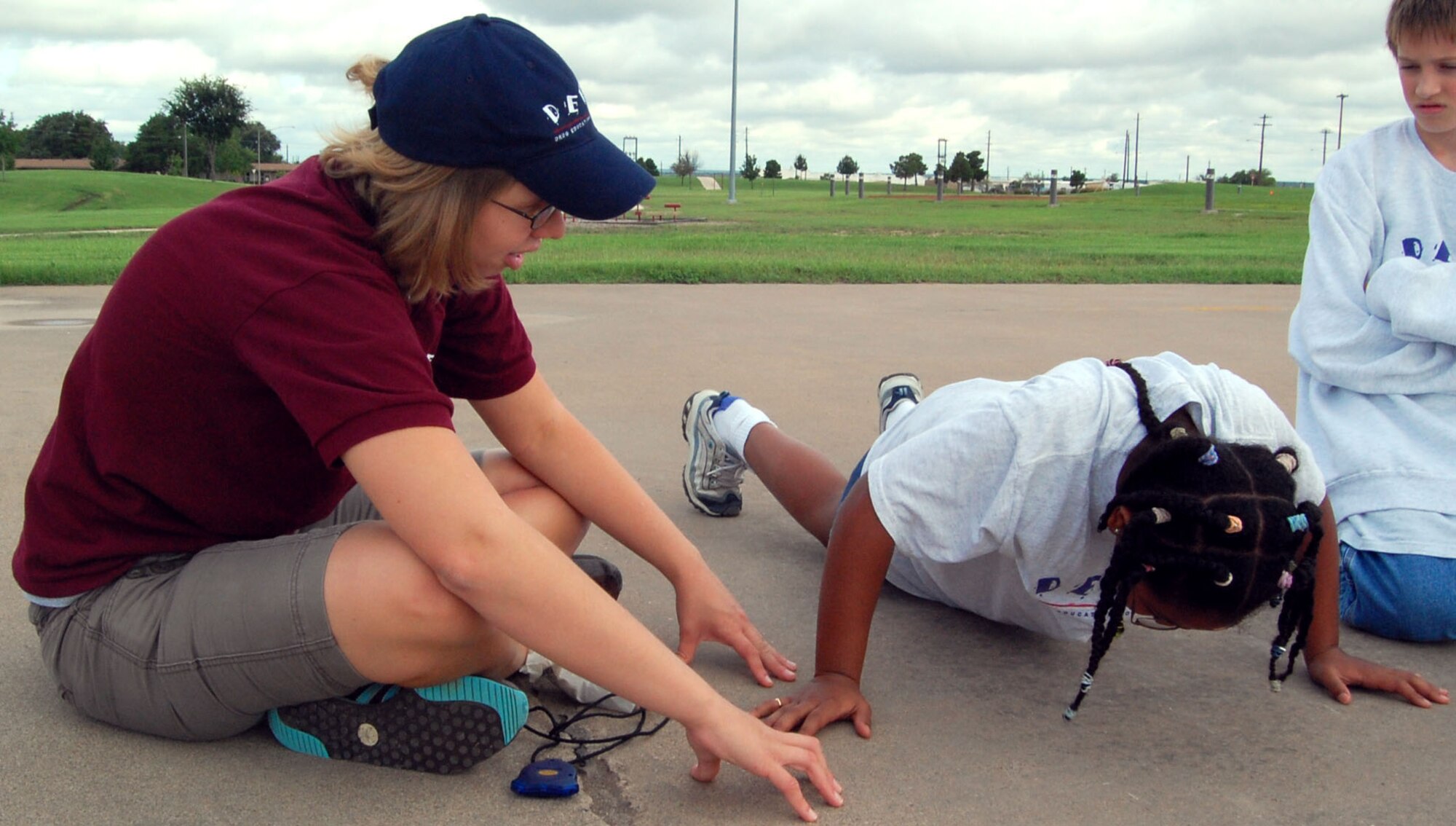LAUGHLIN AIR FORCE BASE , Texas -- Airman Lindy Leggett, 47th Aeromedical Dental Squadron, motivates Alexis Wise, daughter of Tech. Sgt. Dalhia Wise, 47th Force Support Squadron, and Alan Wise, to do as many push-ups as she can during the "President's Challenge" with the Drug Education For Youth summer program July 25. The President's Challenge is a program DEFY holds every year to test the members' physical abilities such as running, stretching and push-ups. (U.S. Air Force photo by Airman Sara Csurilla)
