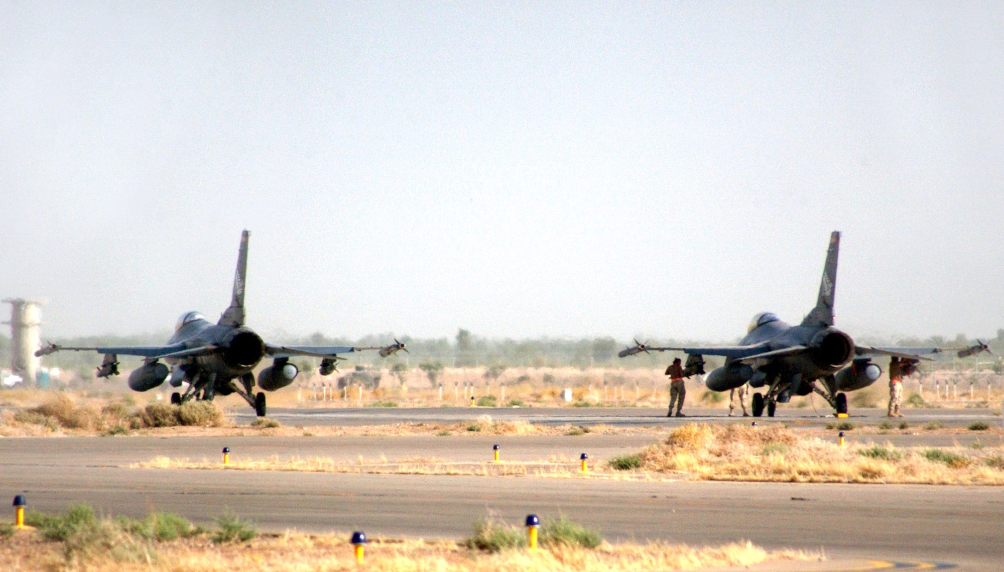 Two F-16 Fighting Falcons go through arming before heading out on a combat mission in support of Operation Iraqi Freedom July 22 at the end of runway at Balad Air Base, Iraq. The two F-16s are deployed from the Oklahoma Air National Guard's 138th Fighter Wing at the Tulsa International Airport. F-16s from the 332nd Air Expeditionary Wing destroyed an al-Qaida training camp southwest of Baghdad July 21. (U.S. Air Force photo/Senior Airman Olufemi A. Owolabi)