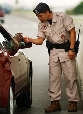 Akimene Hiroaki, a Japanese security guard at Kadena Air Base, Japan, wears the new civilian guard uniform while checking identification cards at Kadena's Gate Two July 27. Kadena's host nation civilian guard force changed uniform colors from dark blue to tan July 26. The guards provide perimeter security, conduct base patrols and perform building security checks throughout the base. (U.S. Air Force photo/Staff Sgt. Reynaldo Ramon)