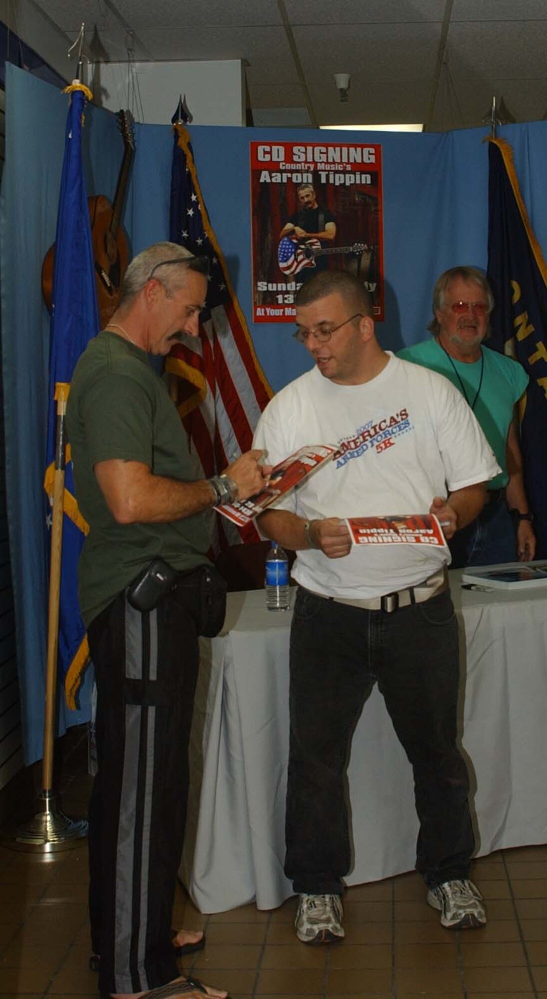 Country music singer Aaron Tippin signs posters of himself for Tech. Sgt. Thomas Shaffer, 741st Missile Security Forces Squadron, who was the first one in line to see the performer when he came to Malmstrom July 29. Mr. Tippin was in town to perform at the Montana State Fair later that evening. (U.S. Air Force photo/Valerie Mullett)