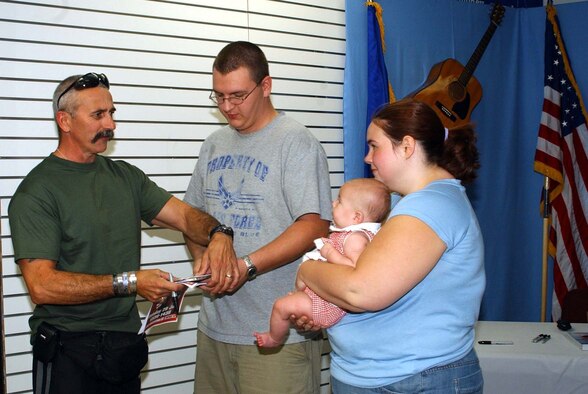 Country singer Aaron Tippin makes faces at 3 1/2-month-old Jasmine, held by mom, Rebekah, as her dad, Airman 1st Class Cody Jacobs gets his CD ready to be autographed. Mr. Tippin was at the Malmstrom base exchange for an hour signing autographs prior to his appearance at the Montana State Fair later that evening. Airman Jacobs is a member of the 341st Missile Maintenance Squadron. (U.S. Air Force photo/Valerie Mullett)